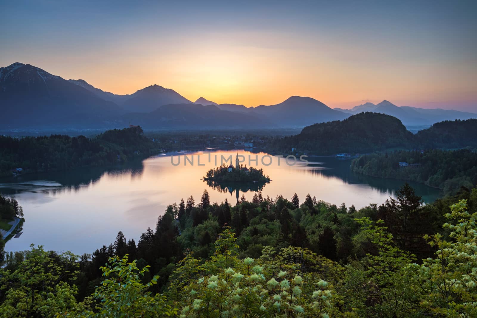 Dramatic sunrise on lake Bled, sunrise view on Bled lake, island, Pilgrimage Church of the Assumption of Maria and Castle with mountain range (Stol, Vrtaca, Begunjscica). Bled, Slovenia,