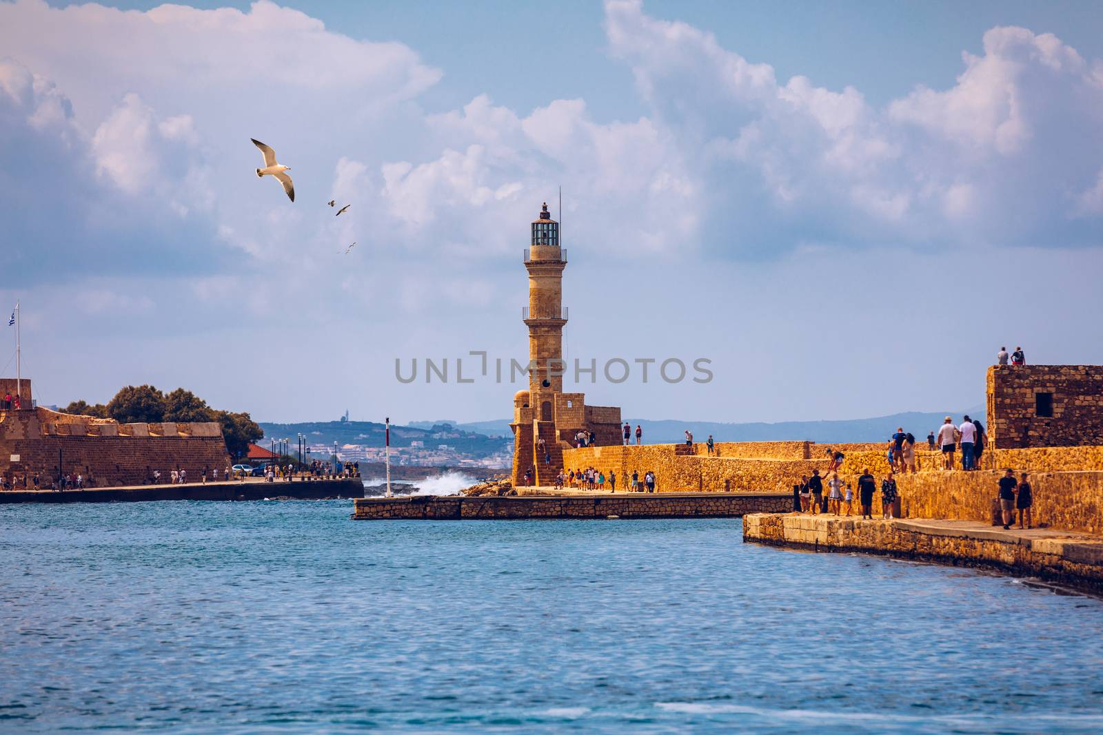 Venetian harbour and lighthouse in old harbour of Chania with seagulls flying over, Crete, Greece. Old venetian lighthouse in Chania, Greece. Lighthouse of the old Venetian port in Chania, Greece.