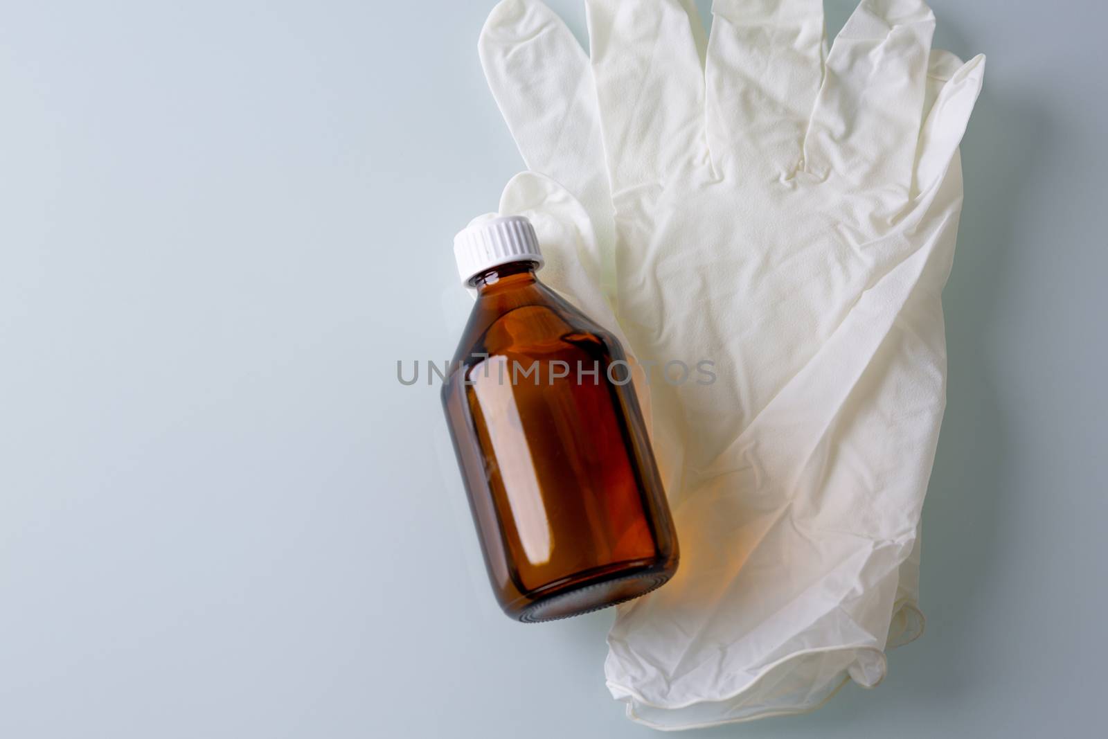 Top view of alcohol solution and rubber gloves on a grey background. Space for text