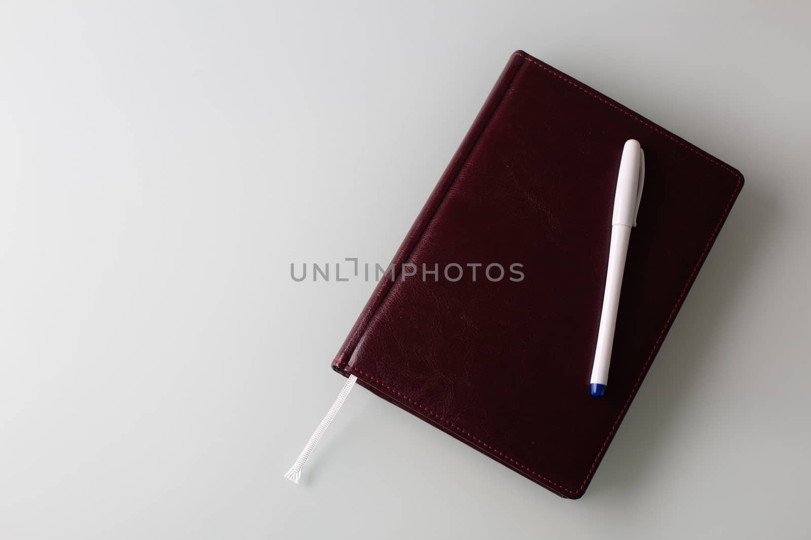 Closeup shot of a pen and a diary in faux leather brown cover. Empty space