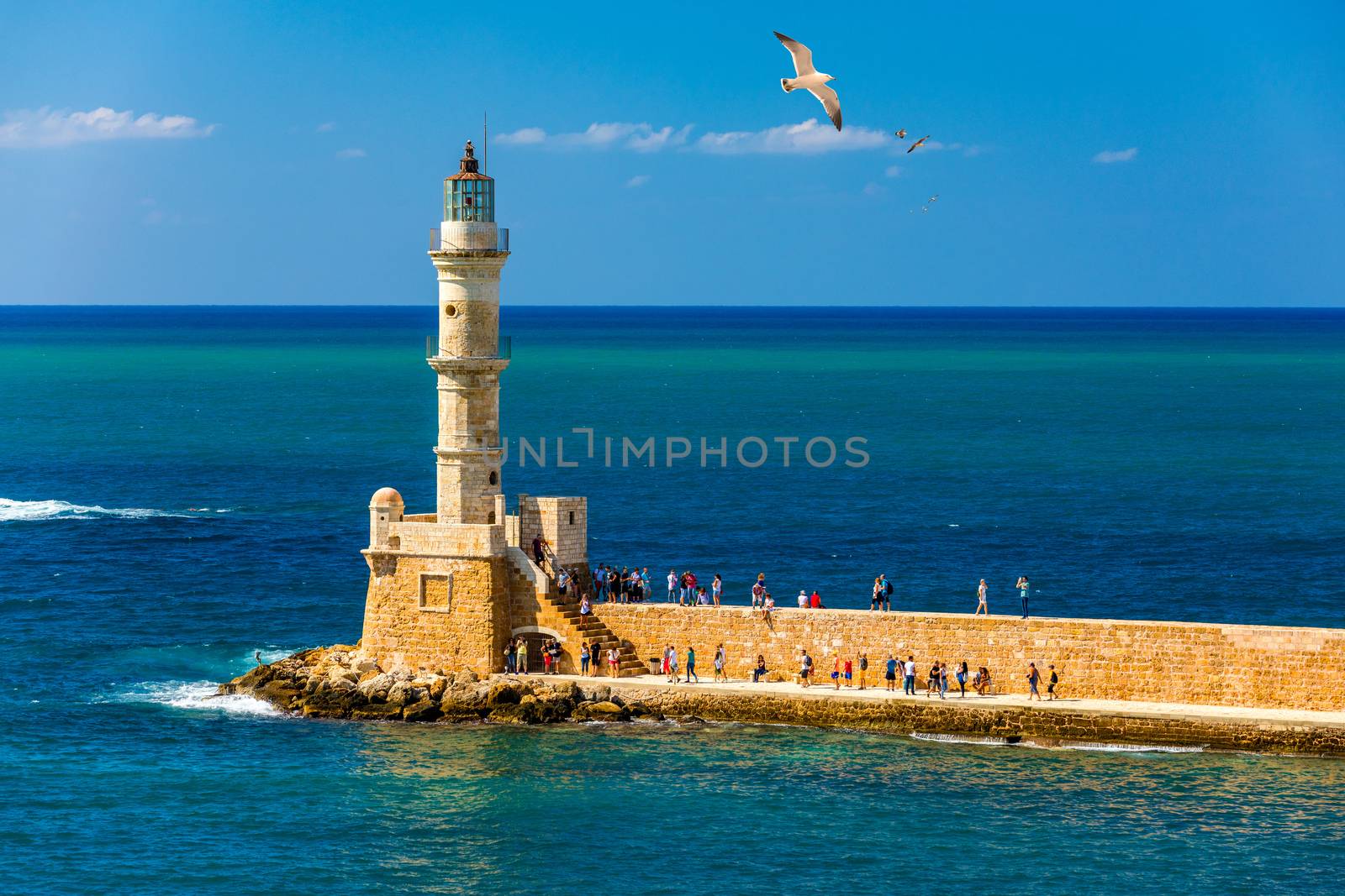 Venetian harbour and lighthouse in old harbour of Chania with seagulls flying over, Crete, Greece. Old venetian lighthouse in Chania, Greece. Lighthouse of the old Venetian port in Chania, Greece.