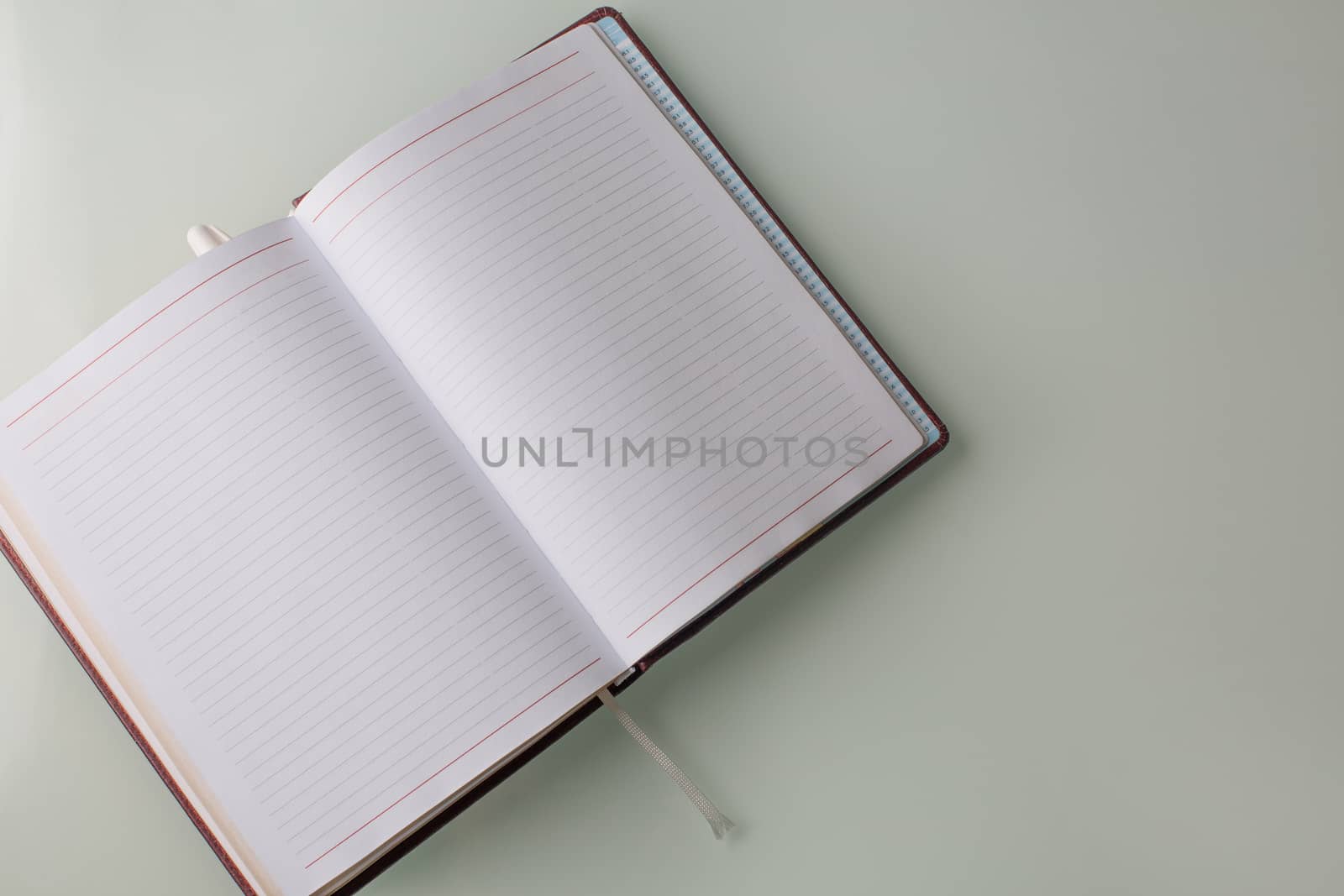 Closeup shot of a pen and a diary on a grey table. Empty space