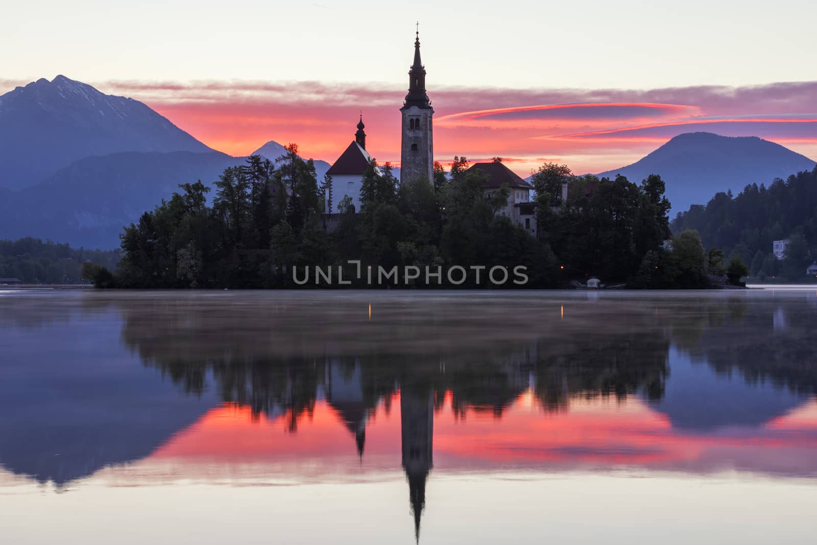Dramatic sunrise on lake Bled, sunrise view on Bled lake, island, Pilgrimage Church of the Assumption of Maria and Castle with mountain range (Stol, Vrtaca, Begunjscica). Bled, Slovenia,