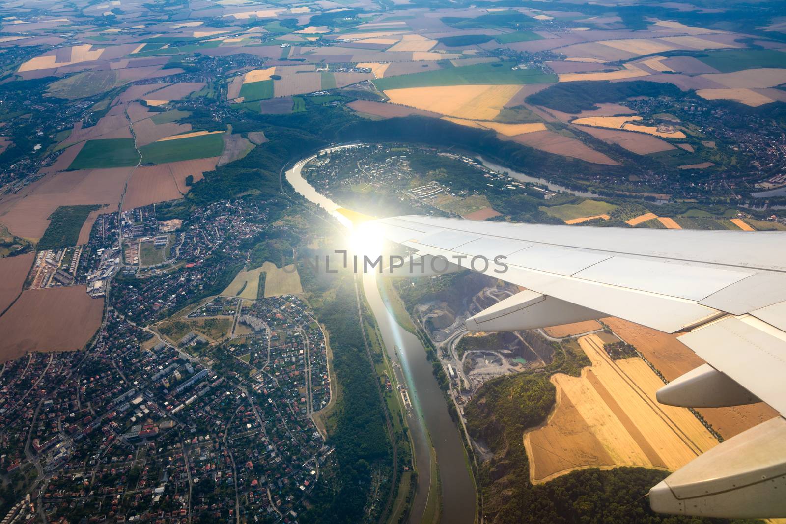 Airplane windows view above the earth on landmark down. View from an airplane window over a wing flying high above farmlands and fields. View from window of plane airplane flying.