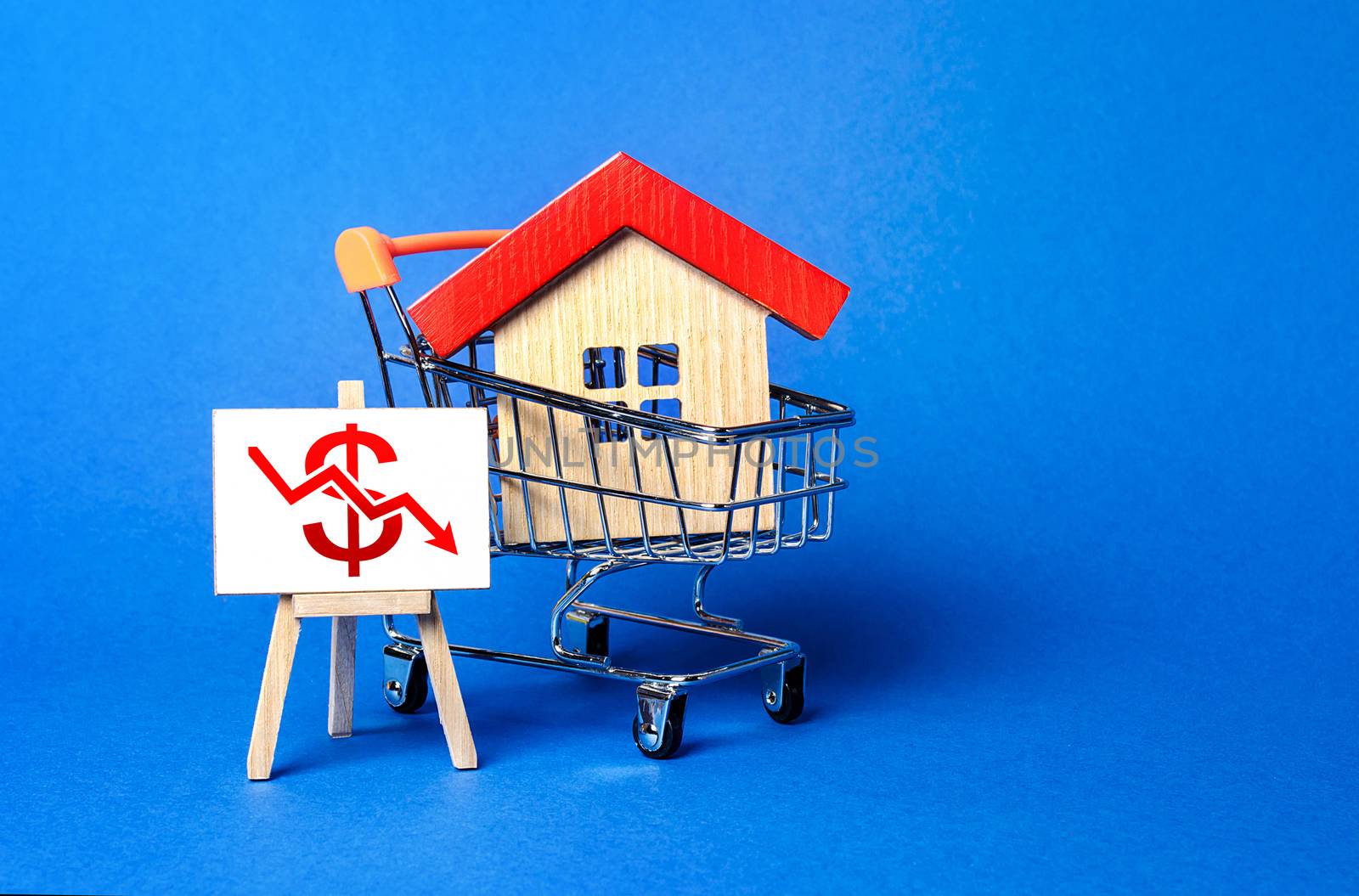 House in a shopping cart and an easel with a red dollar arrow down chart. Fall of real estate market. Cheap rent. Reduced demand, recession. Value cost decrease. Bad attractiveness. Low sales