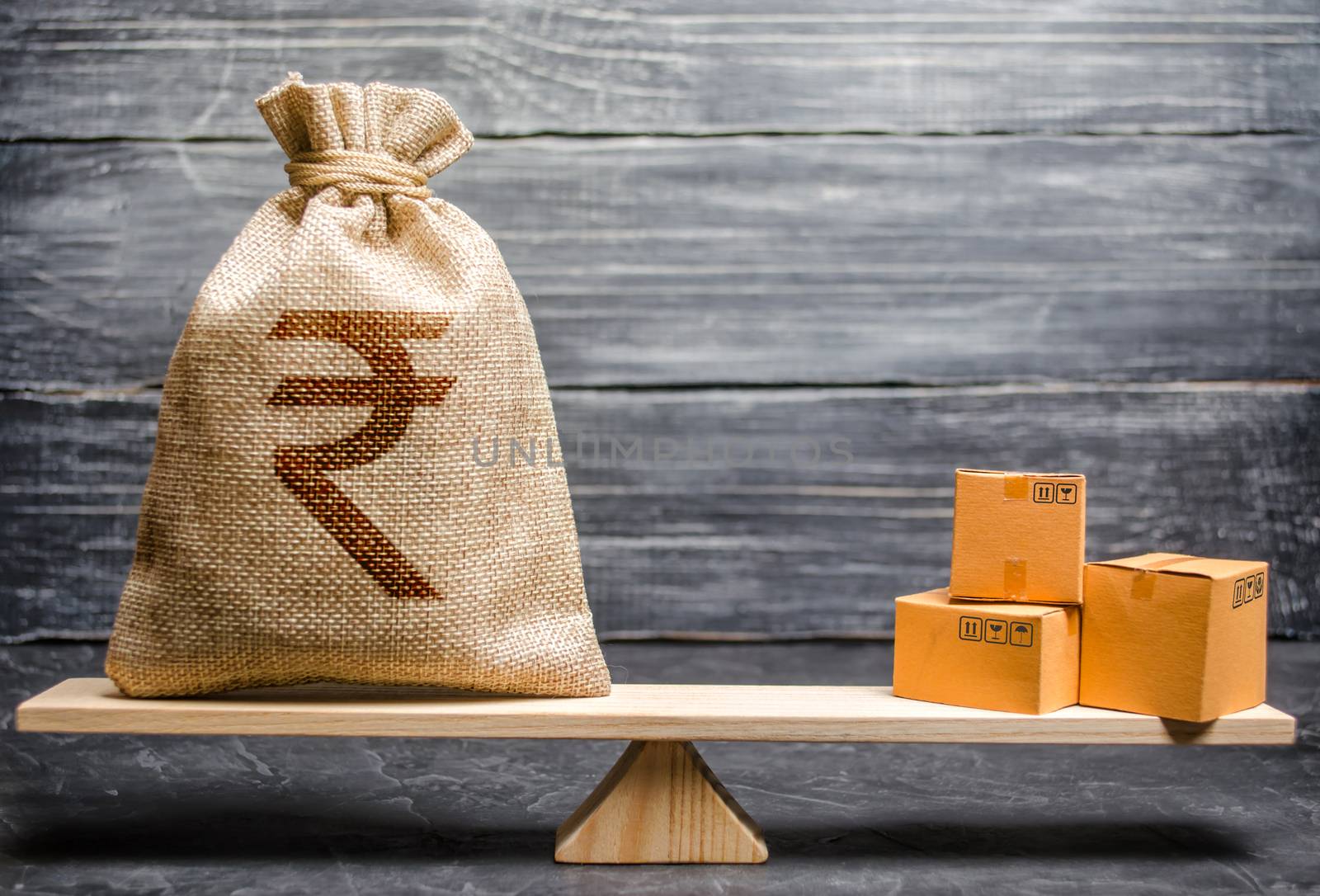 Indian rupee INR symbol money bag and a bunch of boxes on scales. Trade exchange balance. Import and export, economic processes. Profit from manufactured goods. Manufacturing, retail distribution