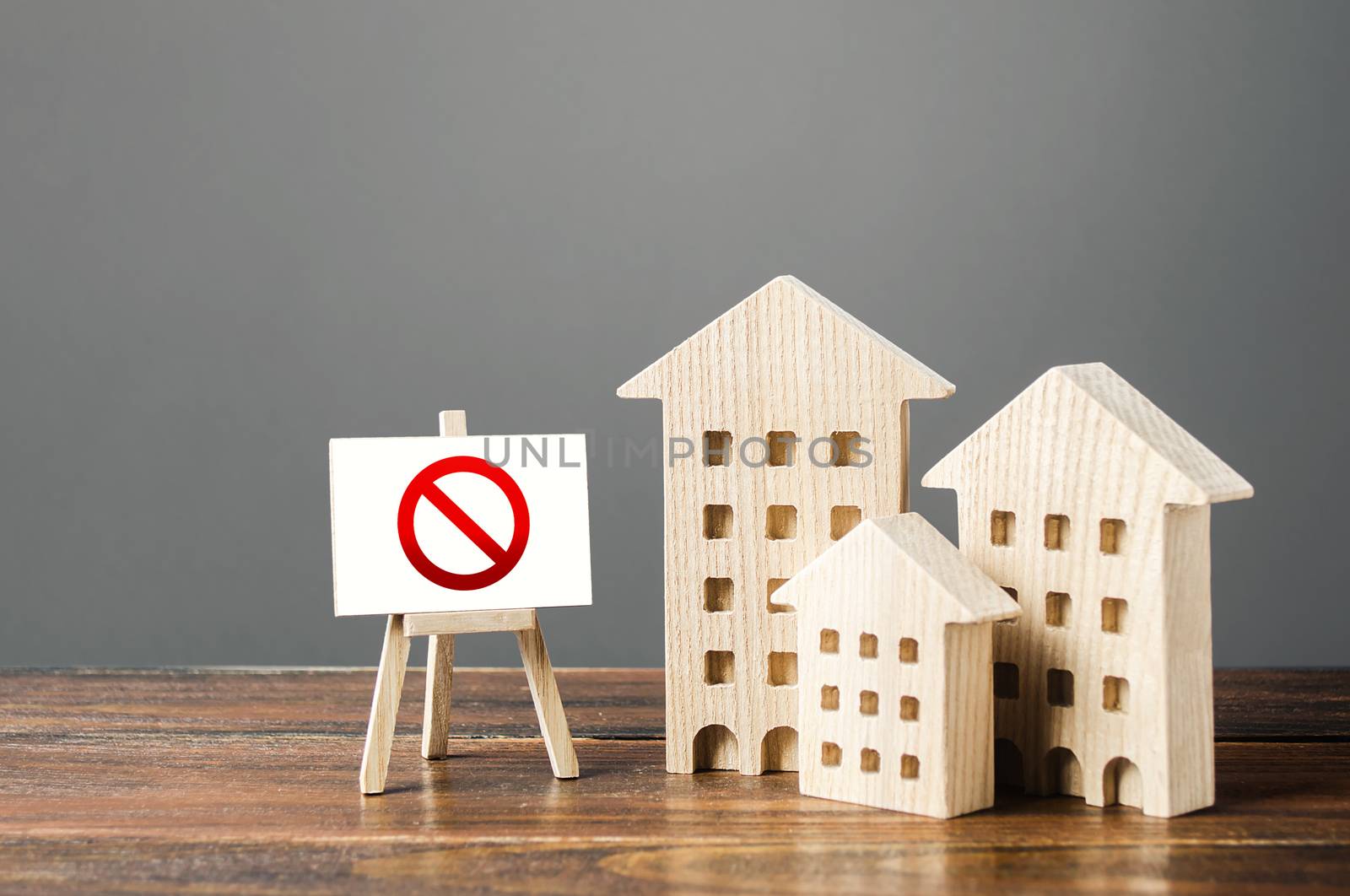 Figures of residential buildings and red prohibition sign no. Inaccessible and expensive housing. Seizure and freezing of assets by a bank, court. Restrictions and a ban on the construction of housing