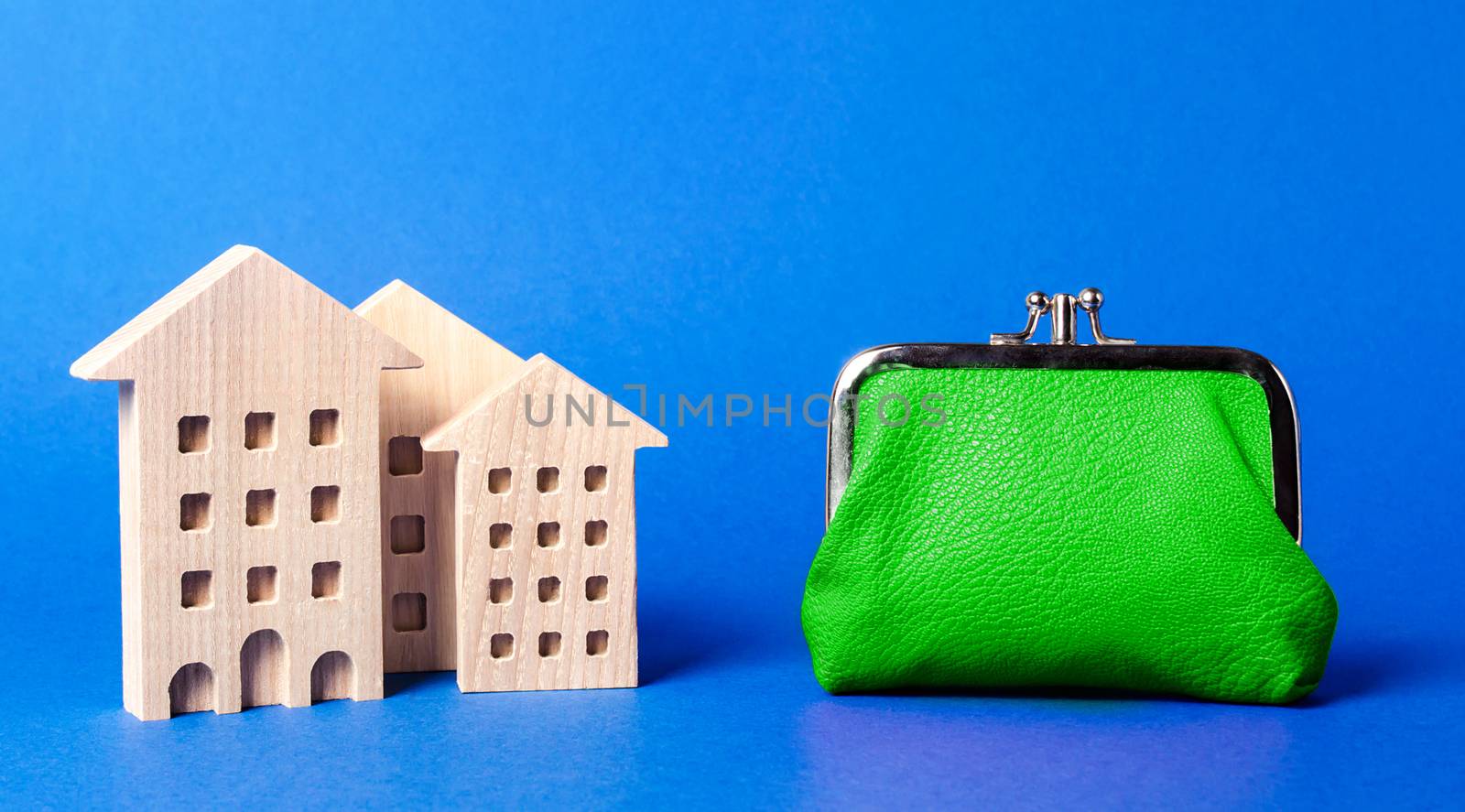 Figures of residential buildings near a large green wallet. concept of the cost of maintaining the building and utility bills. Modernization of housing, improving energy efficiency. Saving to buy home