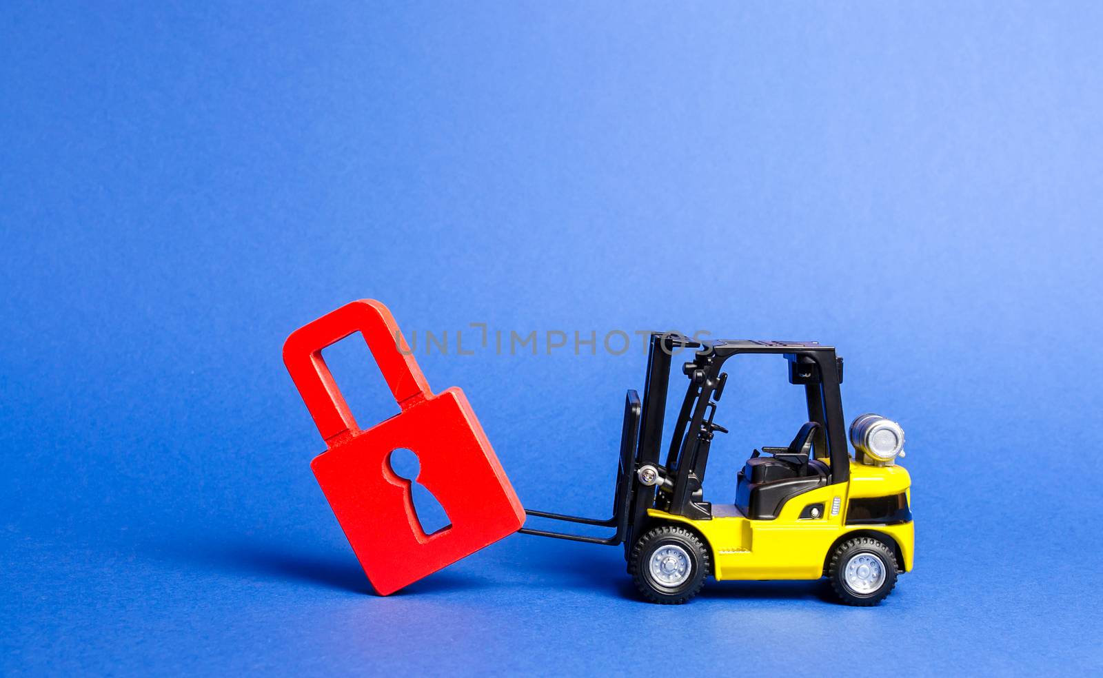 A yellow forklift tilts a red padlock from the road. Bypassing prohibitions and sanctions restrictions, lobbying the interests of industry in government. Loopholes in the laws, overcoming bans. by iLixe48