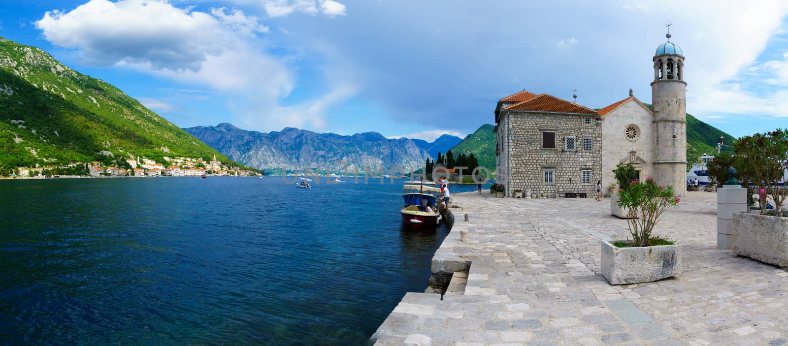 PERAST, MONTENEGRO - JUNE 28, 2015: Panoramic view of Our Lady of the Rocks church, and the town of Perast, with local and tourists. The Bay of Kotor, Montenegro