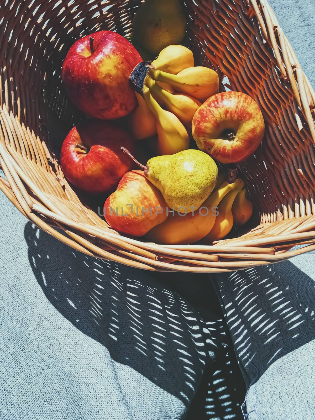 Organic apples, pears and bananas on rustic in a wicker basket by Anneleven