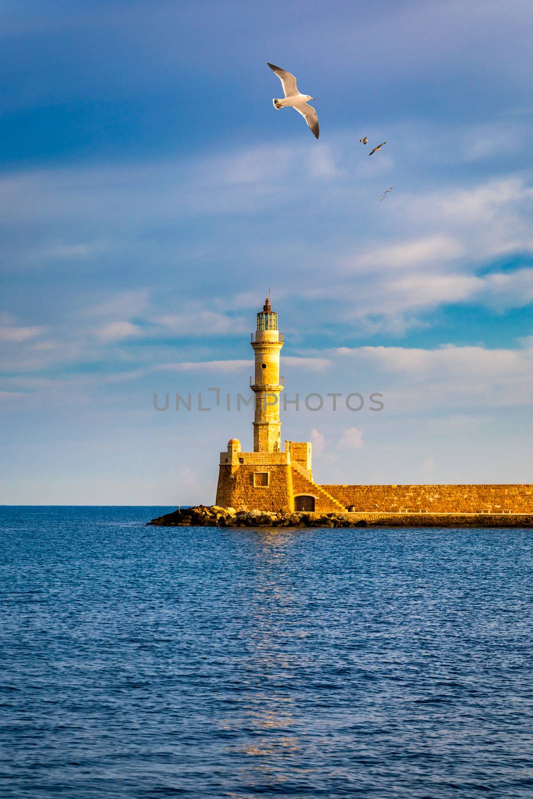 Venetian harbour and lighthouse in old harbour of Chania with seagulls flying over, Crete, Greece. Old venetian lighthouse in Chania, Greece. Lighthouse of the old Venetian port in Chania, Greece.