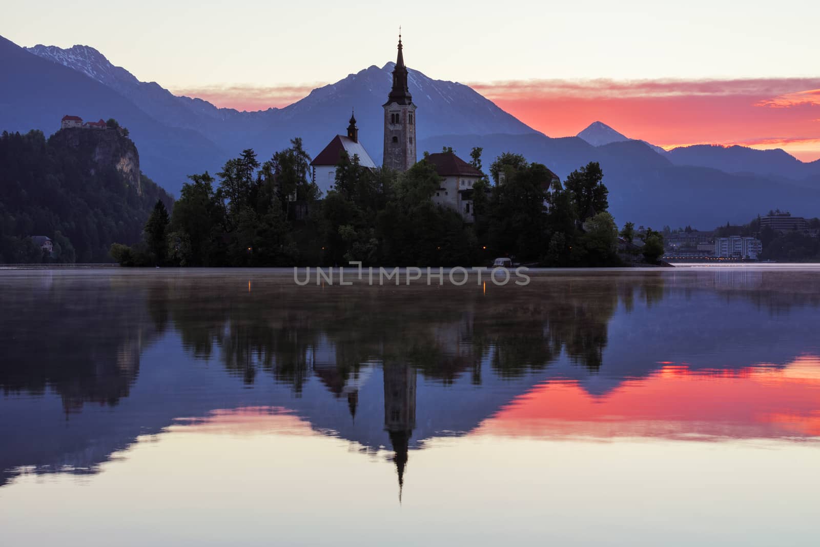 Dramatic sunrise on lake Bled, sunrise view on Bled lake, island, Pilgrimage Church of the Assumption of Maria and Castle with mountain range (Stol, Vrtaca, Begunjscica). Bled, Slovenia,