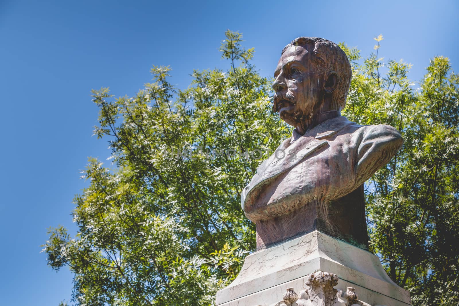 Evora, Portugal - May 5, 2018: View of a public garden on a spring day with a statue of Francisco Eduardo de Barahona Fragoso sculpted by the Portuguese Jose Simoes de Almeida