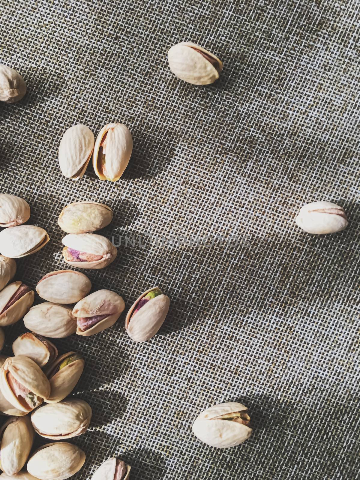 Pistachio nuts on rustic linen background, food and nutrition