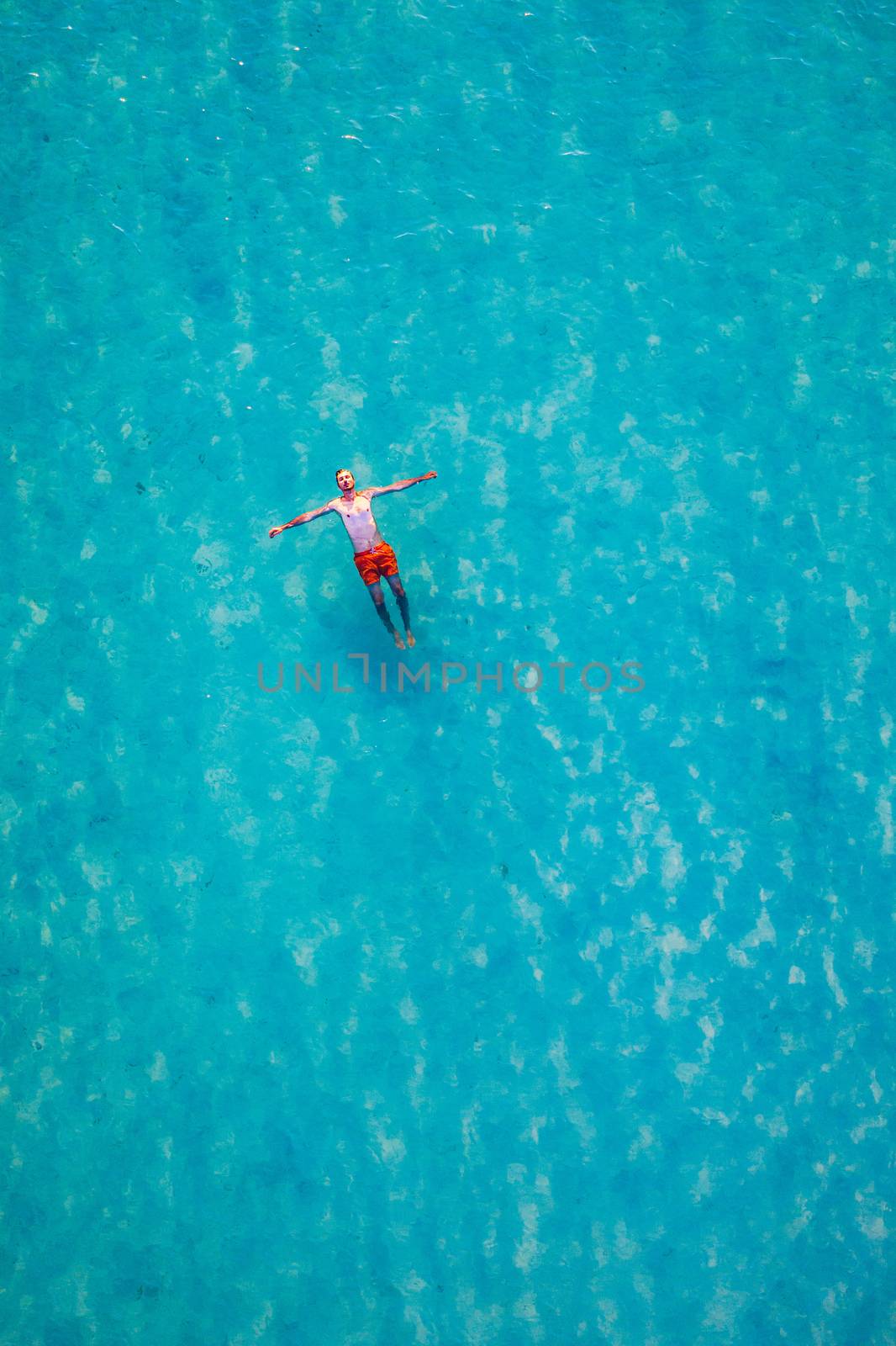 Drone view of a man floating in tropical sea water. Aerial view  by DaLiu
