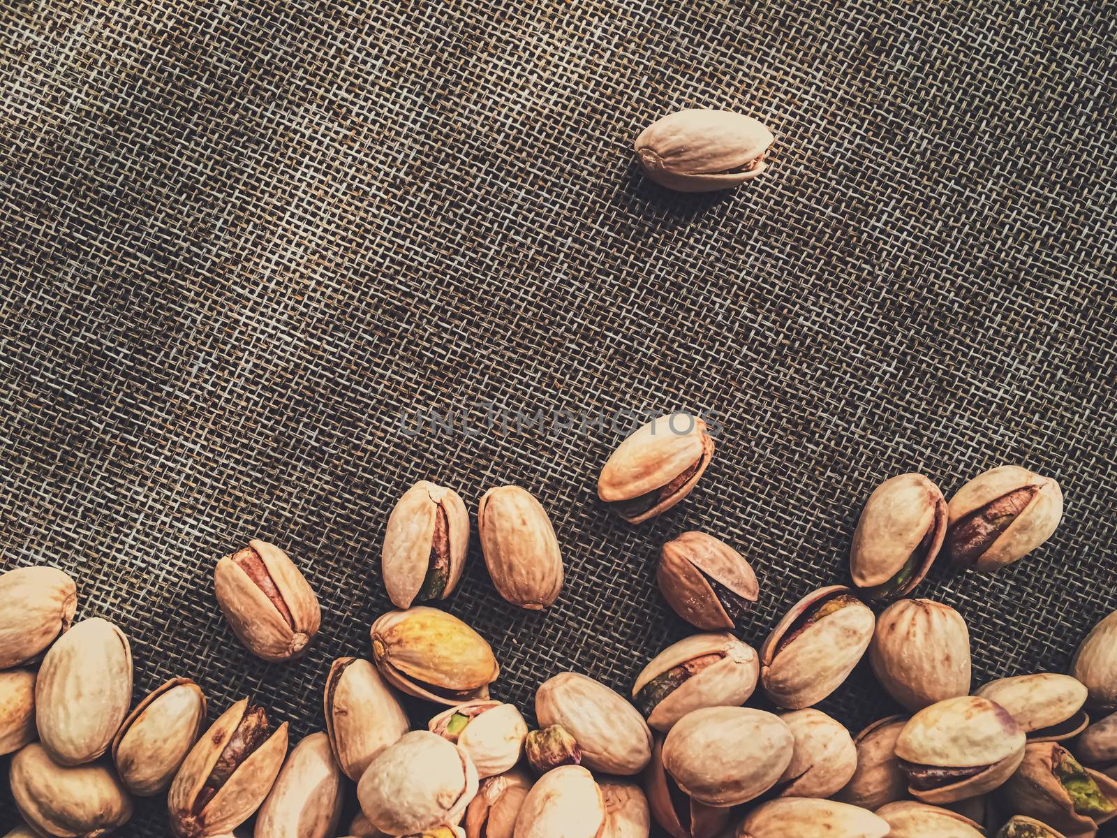 Pistachio nuts on rustic linen background, food and nutrition