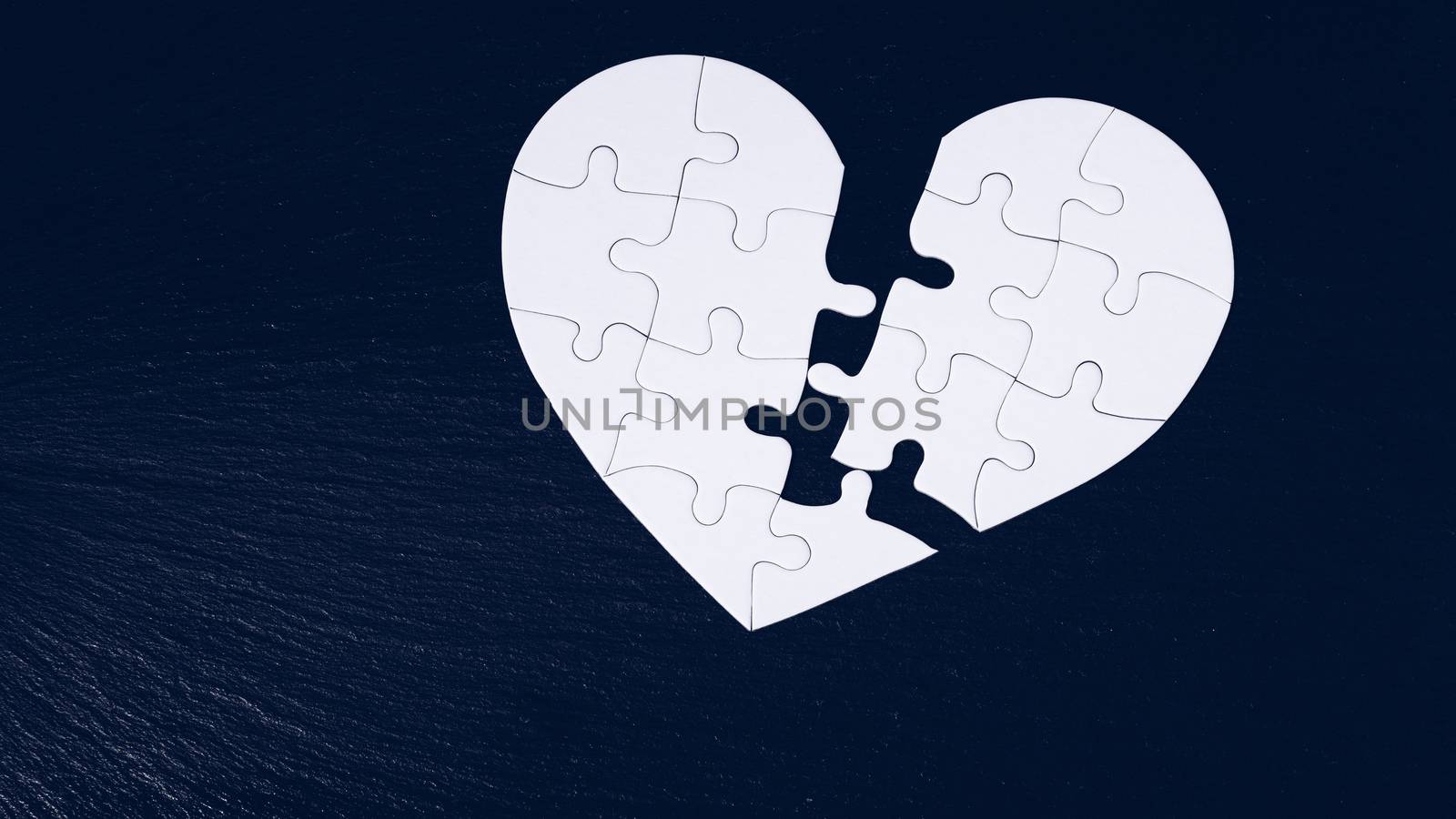 Heart jigsaw split in half, valentine's day, two piece jigsaw love heart puzzle, love concept. Puzzle heart on black wooden background. Heart-shaped jigsaw puzzle on black background