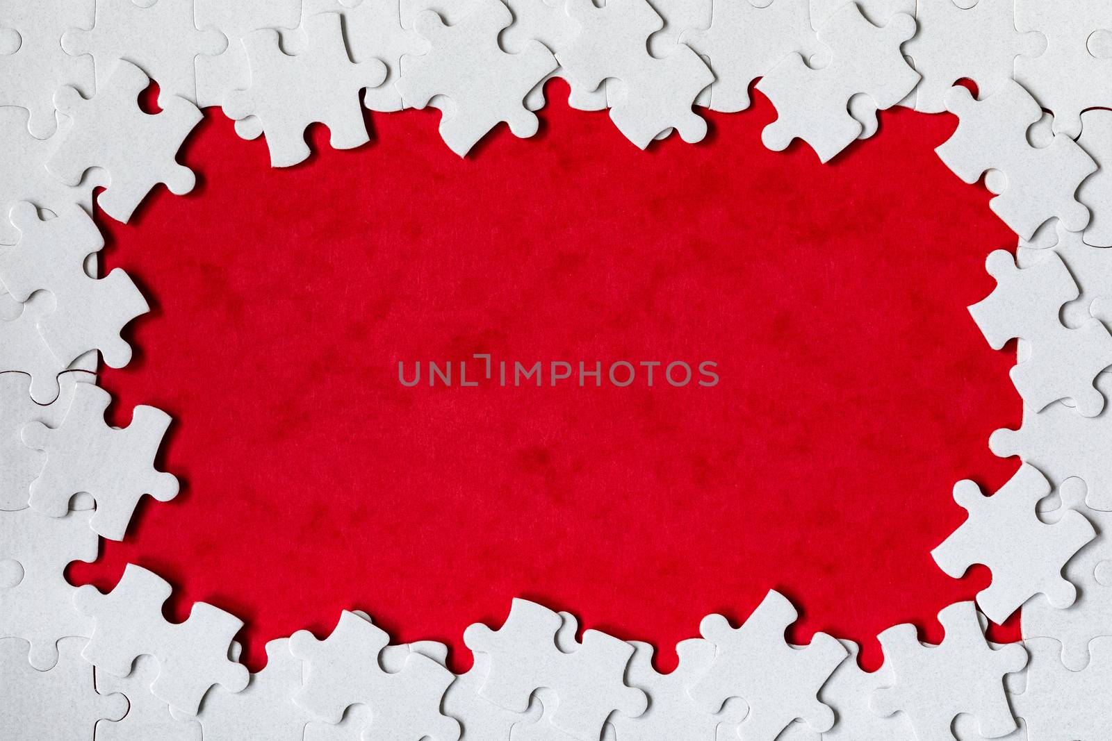 Framing in the form of a rectangle, made of a white jigsaw puzzle. Frame text and jigsaw puzzles. Frame made of jigsaw puzzle pieces on red background.