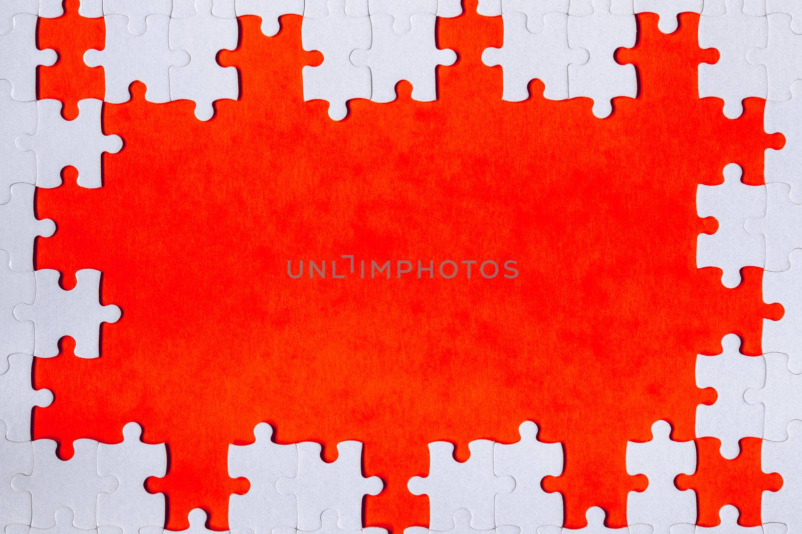 Framing in the form of a rectangle, made of a white jigsaw puzzle. Frame text and jigsaw puzzles. Frame made of jigsaw puzzle pieces on orange background.