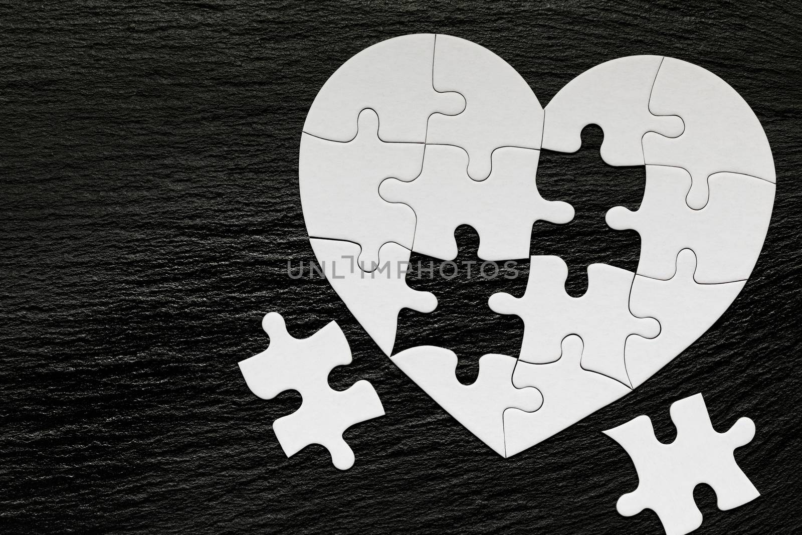 Heart-shaped jigsaw puzzle on color background. Puzzle heart on wooden background. A missing piece of the heart puzzle. Heart shape jigsaw puzzle. Puzzles in the shape of a heart. 