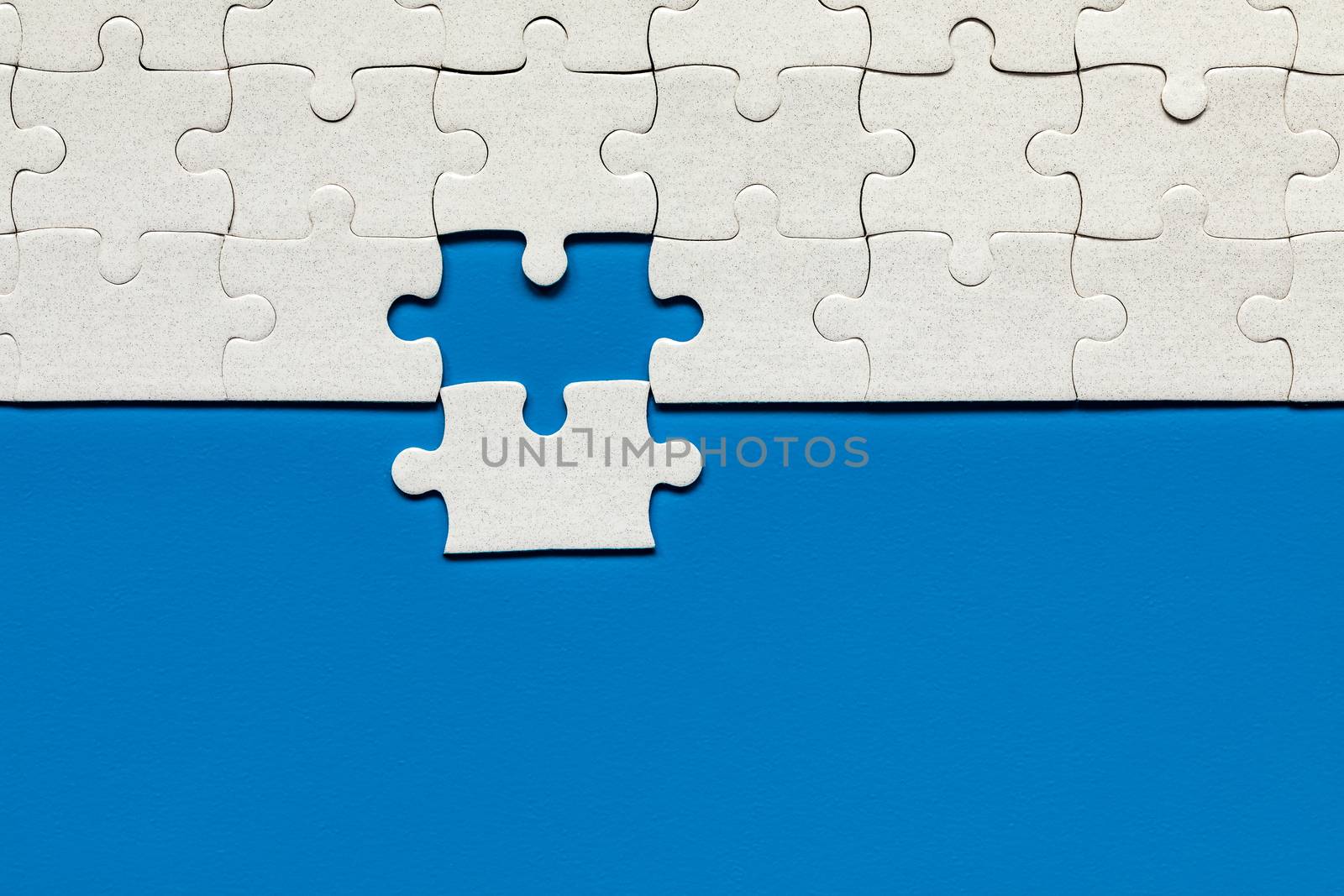 White jigsaw puzzle. White puzzle pieces on color background. Unfinished white jigsaw puzzle pieces on color background. 