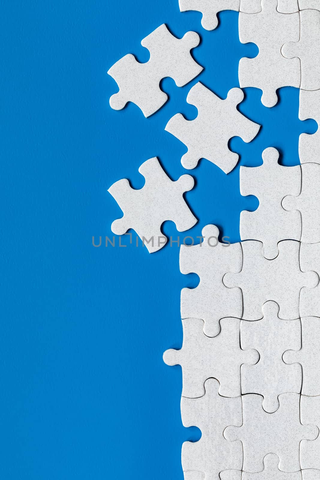 White jigsaw puzzle. White puzzle pieces on color background. Unfinished white jigsaw puzzle pieces on color background. 
