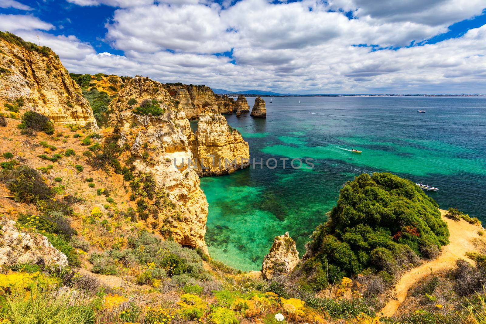 Panoramic view, Ponta da Piedade near Lagos in Algarve, Portugal. Cliff rocks and tourist boat on sea at Ponta da Piedade, Algarve region, Portugal. Ponta da Piedade, Algarve region, Portugal.
