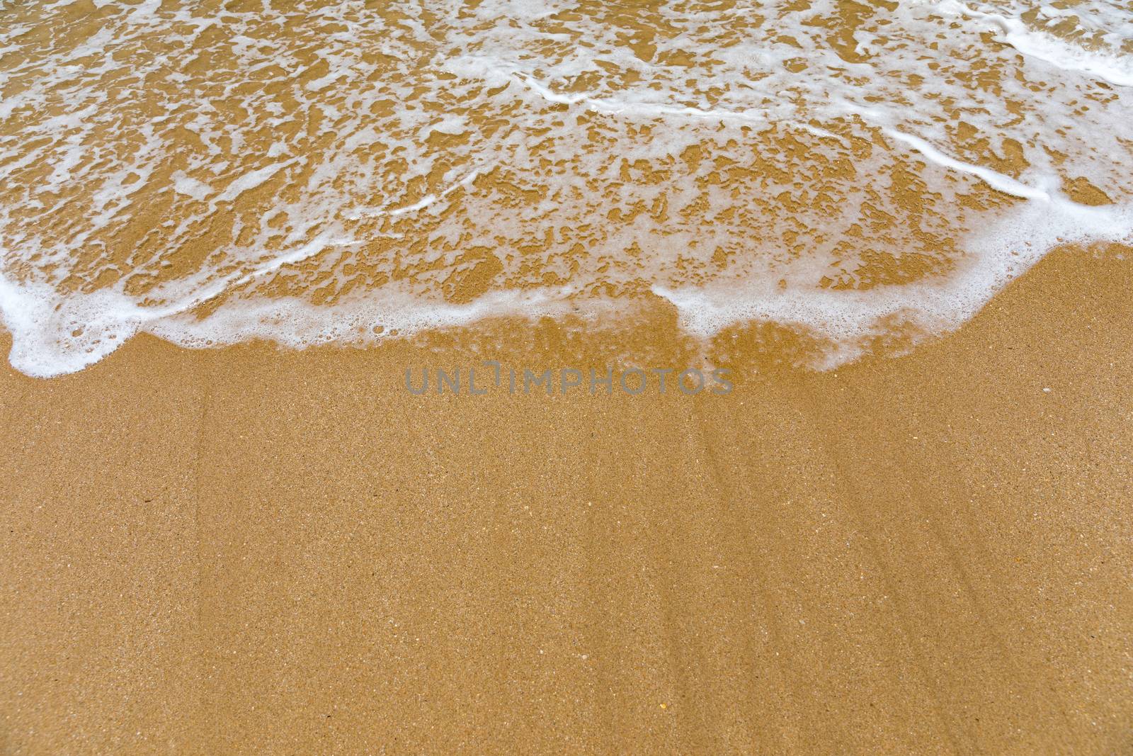 Blue ocean wave on sandy beach. Soft wave of blue ocean on sandy beach. Background. Top view of Beautiful beach with tranquil wave, sea and ocean background, summer vacation concept. 