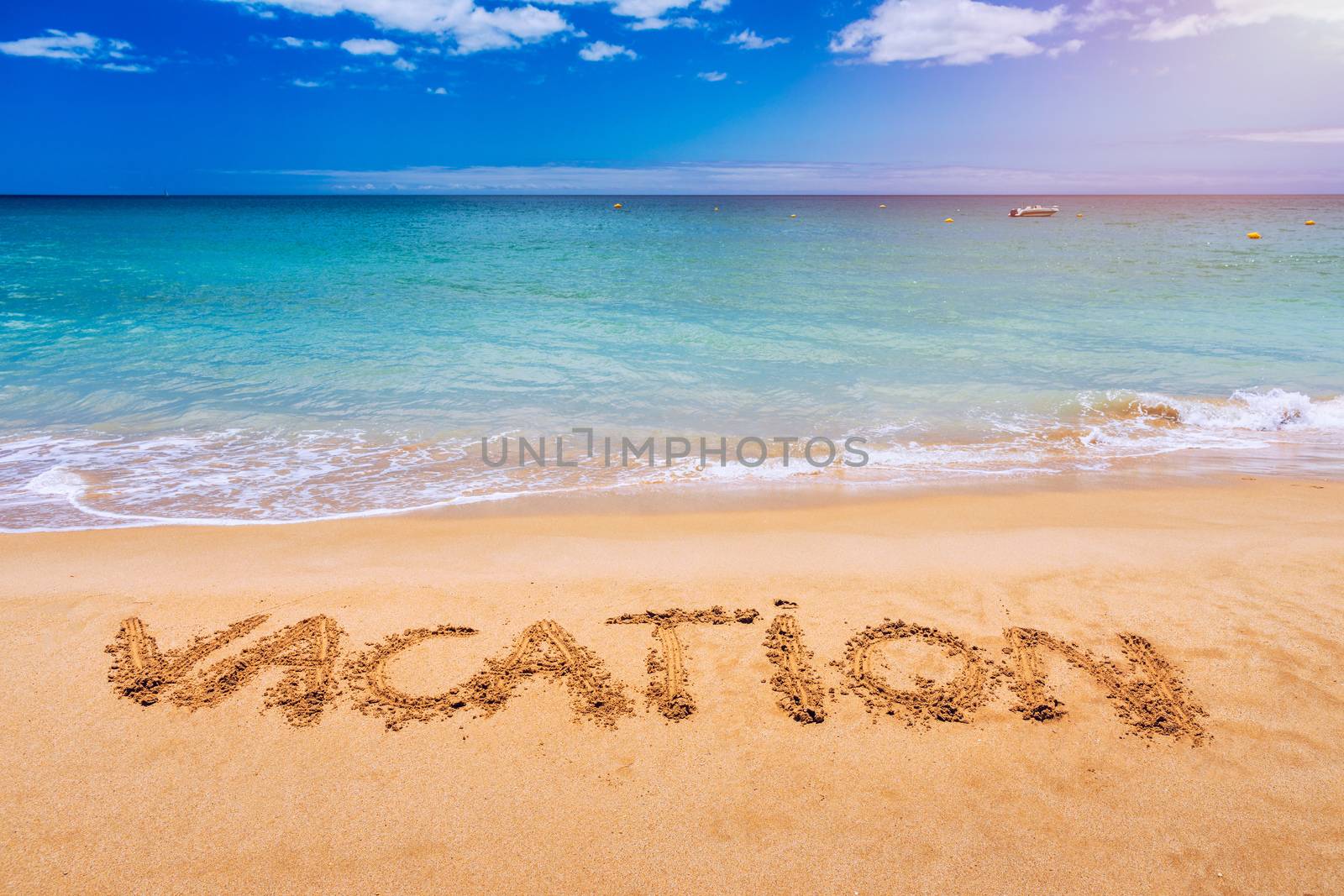 Vacation text on a beach. Vacation written in a sandy tropical beach. "Vacation" written in the sand on the beach blue waves in the background. Vacation on the sand beach concept.