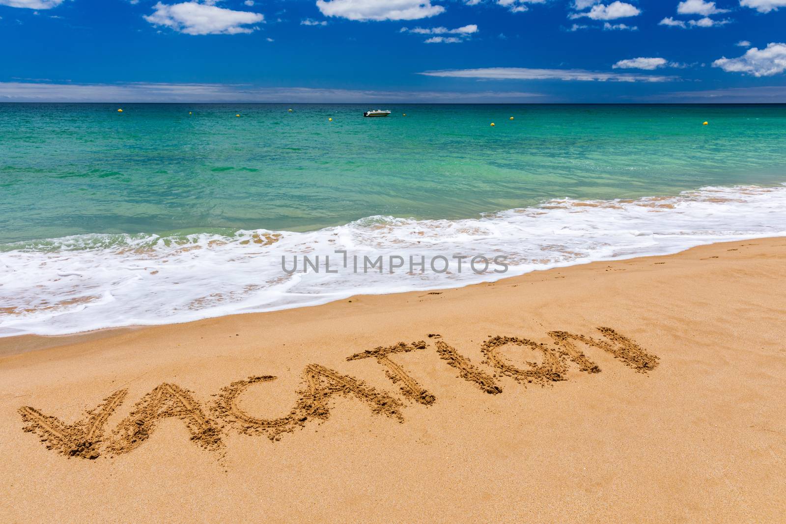 Vacation text on a beach. Vacation written in a sandy tropical beach. "Vacation" written in the sand on the beach blue waves in the background. Vacation on the sand beach concept.