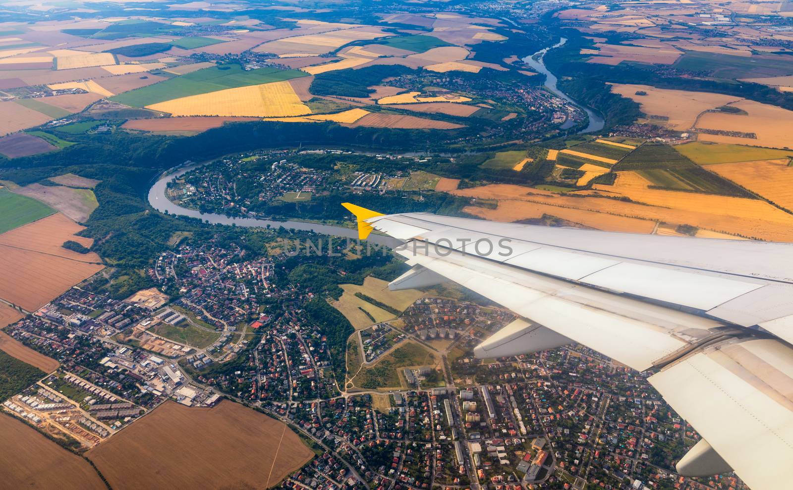 Airplane windows view above the earth on landmark down. View from an airplane window over a wing flying high above farmlands and fields. View from window of plane airplane flying.