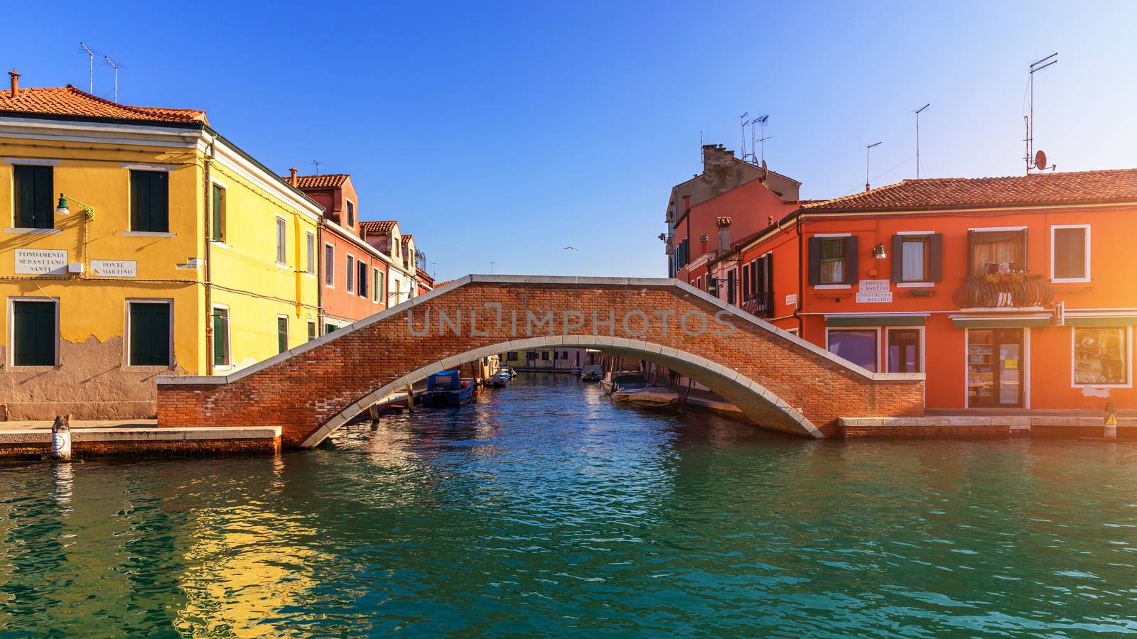 Street canal in Murano island, Venice. Narrow canal among old colorful brick houses in Murano, Venice. Murano postcard, Venice, Italy.