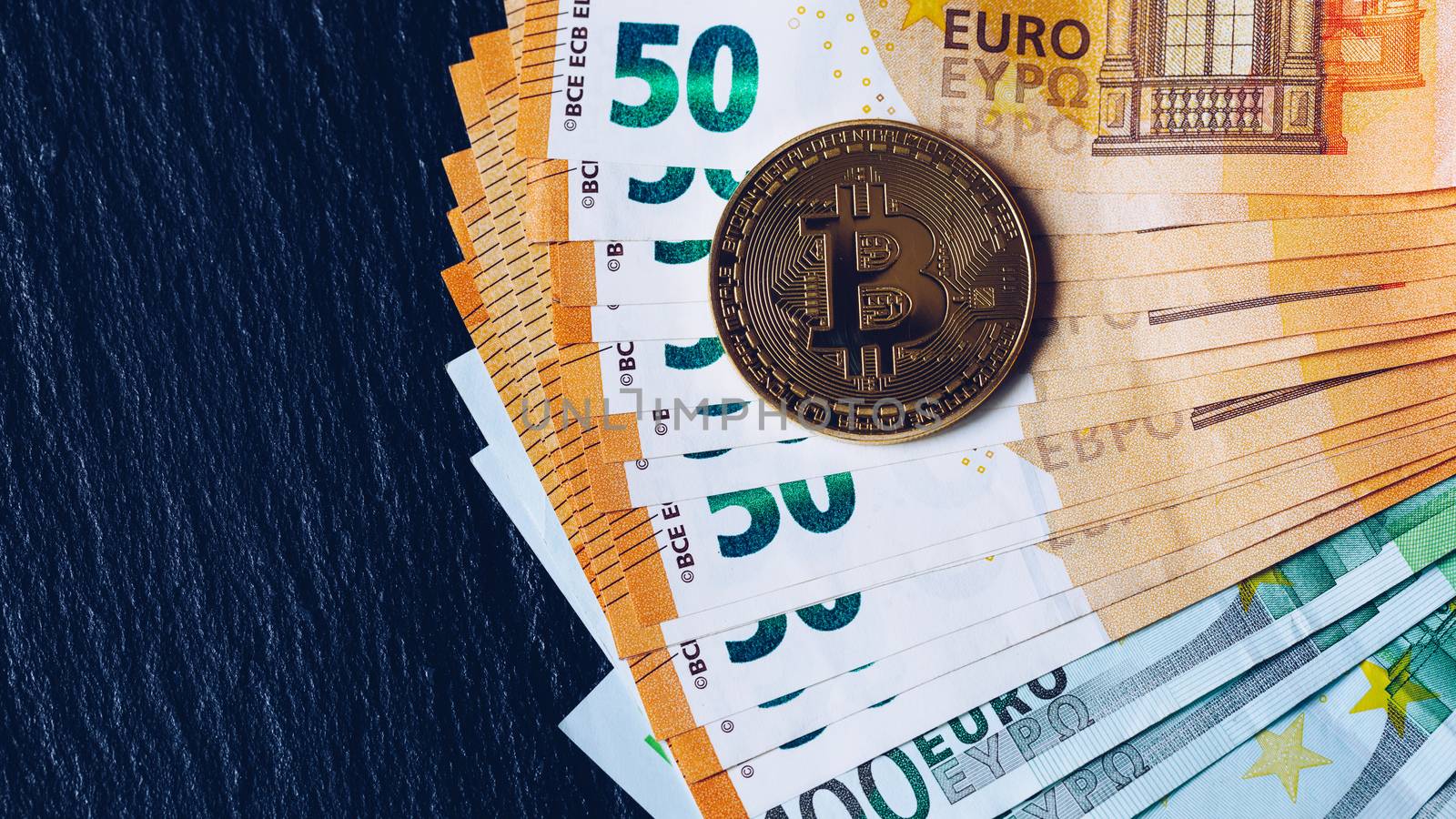 Golden bitcoin over Euro money. Bitcoin cryptocurrency. Crypto currency concept. Bitcoin with euro bills. Bitcoins stacked on euro banknotes.