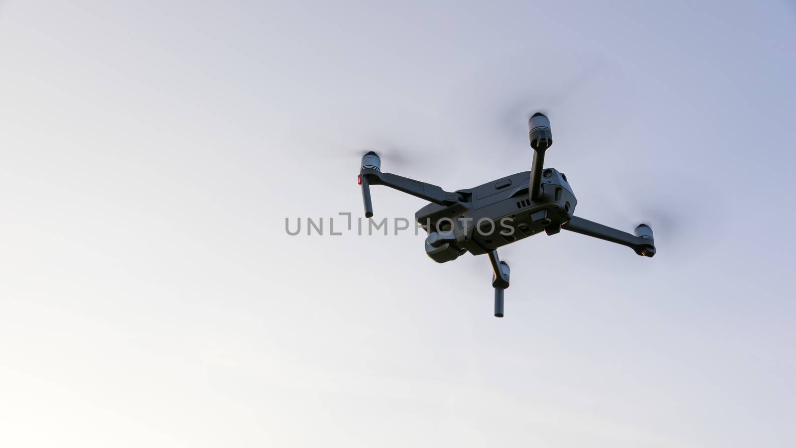 Drone flying over landscape. UAV drone copter flying with digital camera. Drone flying overhead in cloudy blue sky. Quad copter is flying over the  field.