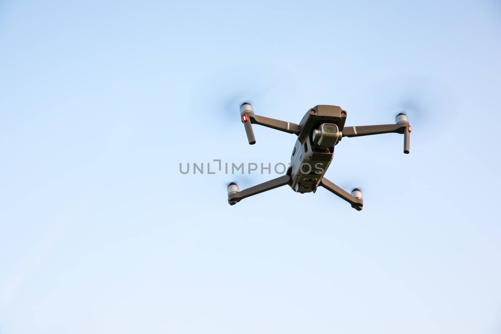 Drone flying over landscape. UAV drone copter flying with digital camera. Drone flying overhead in cloudy blue sky. Quad copter is flying over the  field.