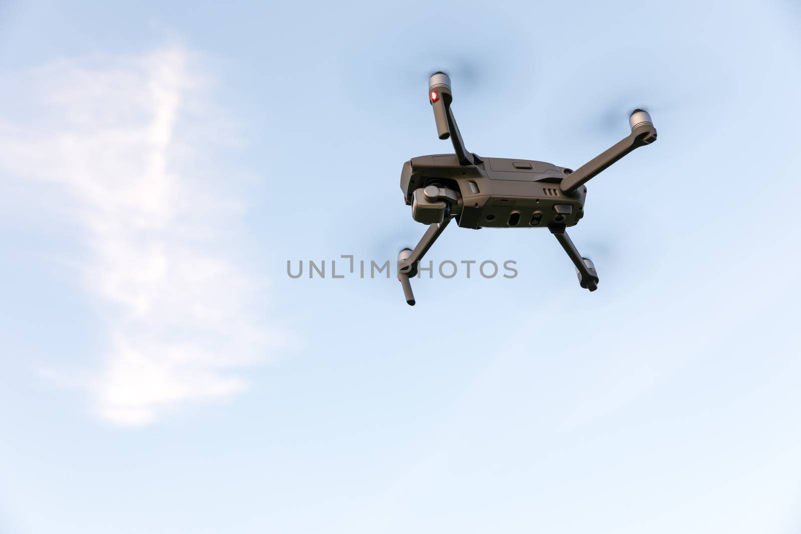 Drone flying over landscape. UAV drone copter flying with digital camera. Drone flying overhead in cloudy blue sky. Quad copter is flying over the  field.