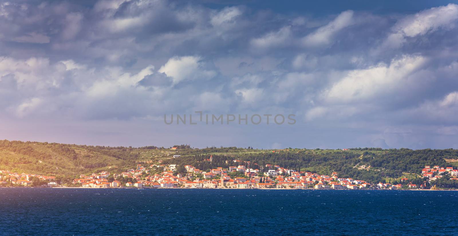 Supetar city in Brac island, Croatia. View from the sea. Picturesque scenic view on Supetar on Brac island, Croatia. Panoramic view on harbor of town Supetar from the side of sea. Brac, Croatia.