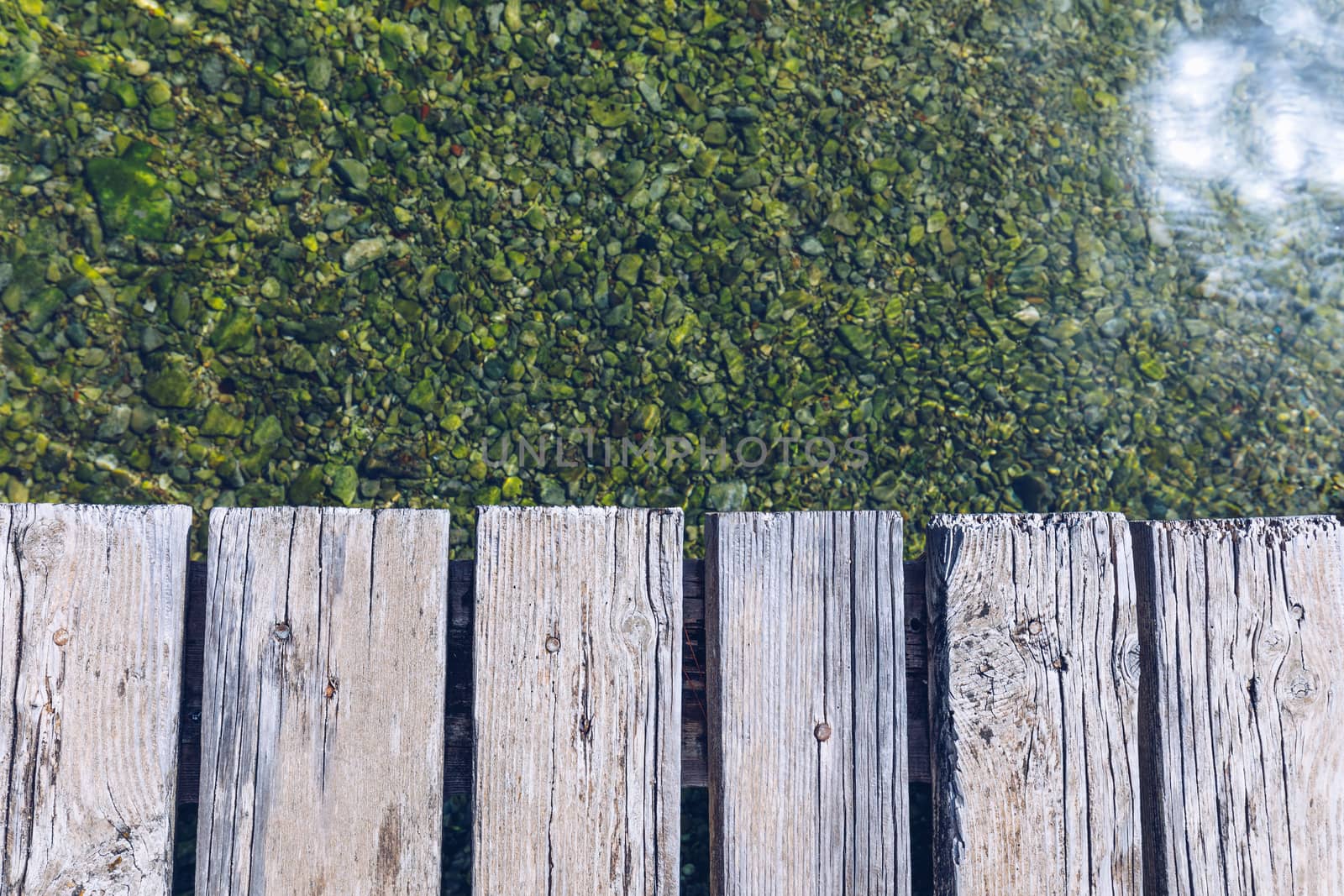 Wooden board empty over sea, can be used for display or present a product. Summer season. Empty perspective wooden planks over the reflection of green water, product display template.