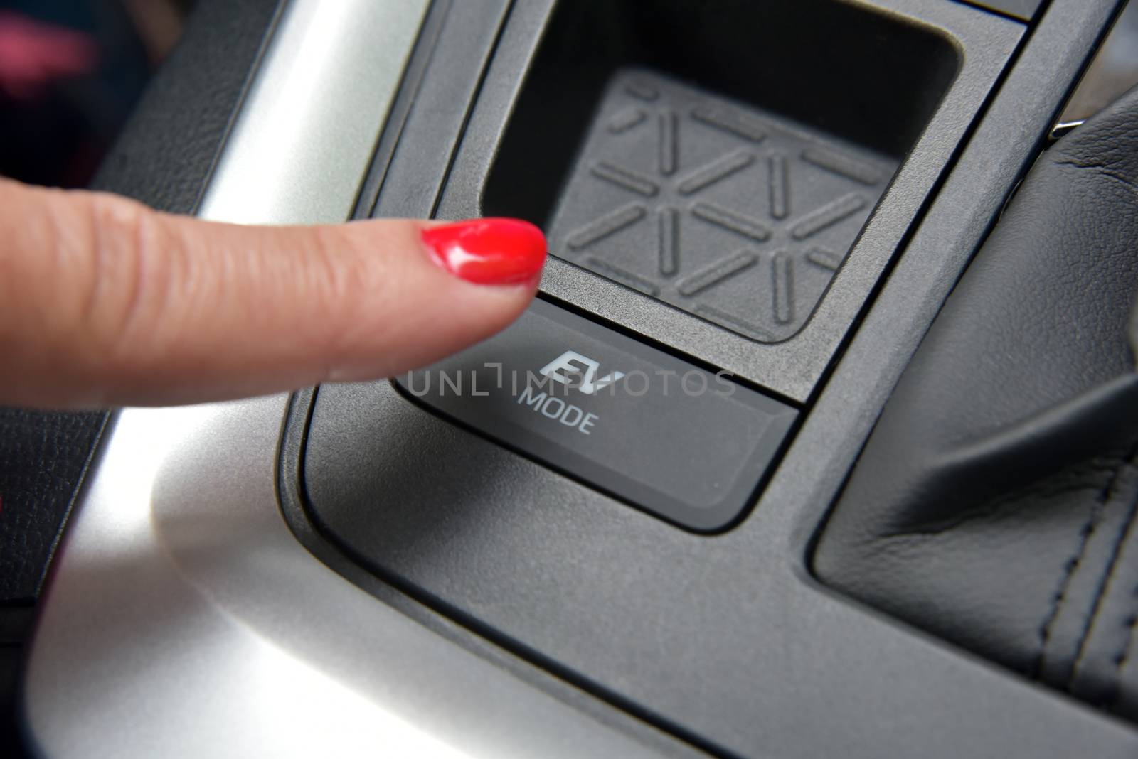the finger of a woman on the switch for the ev mode of a hybrid car
