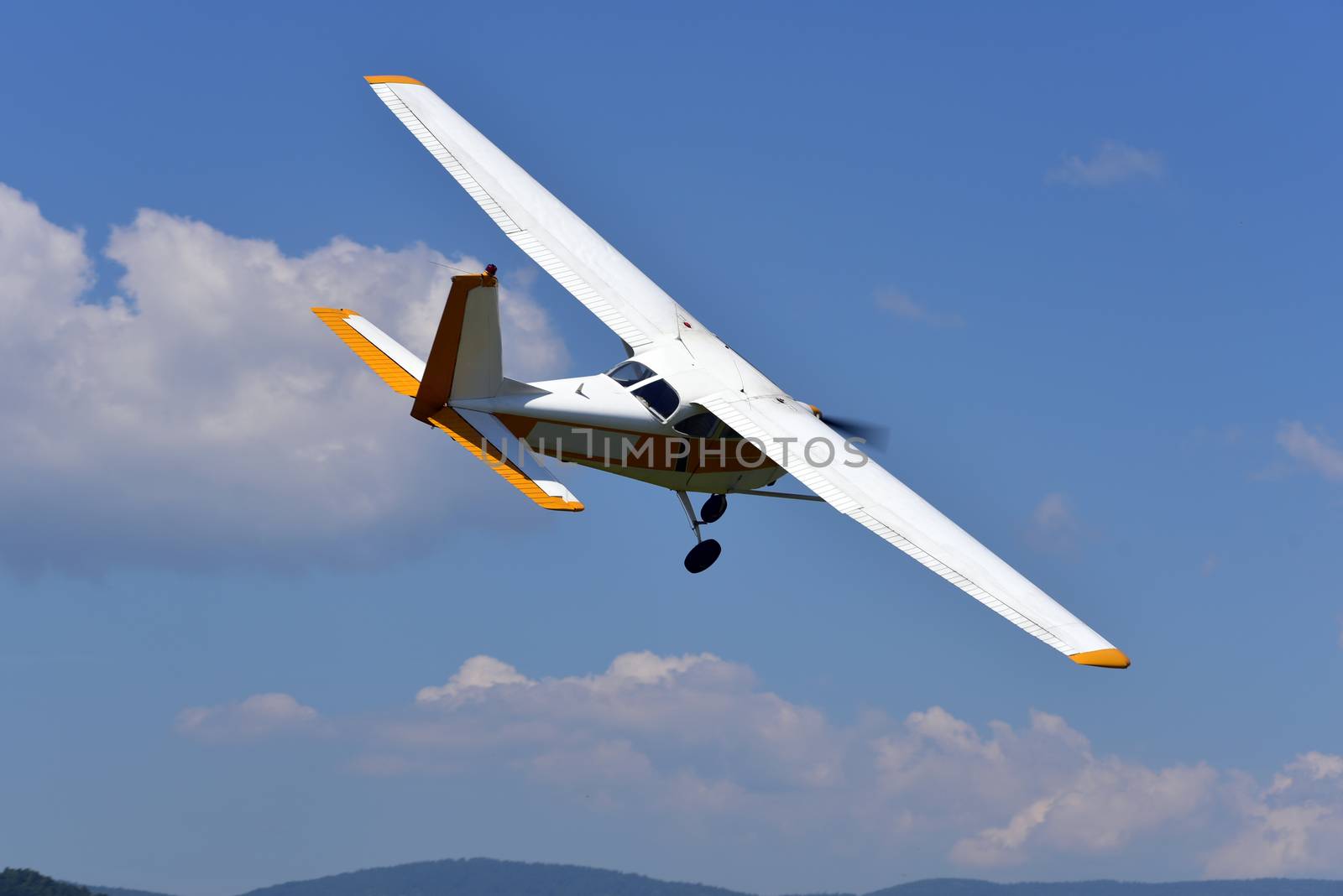 A small single engine aircraft flying in the blue sky