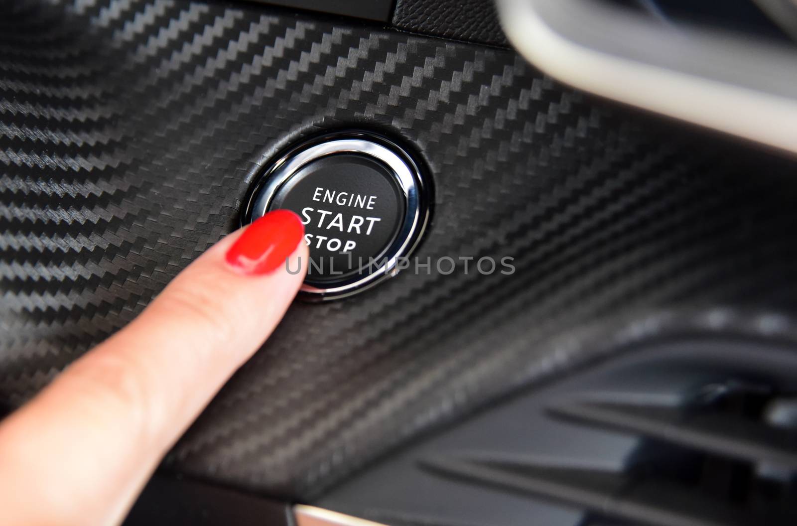 Female finger on the button to activate car engine