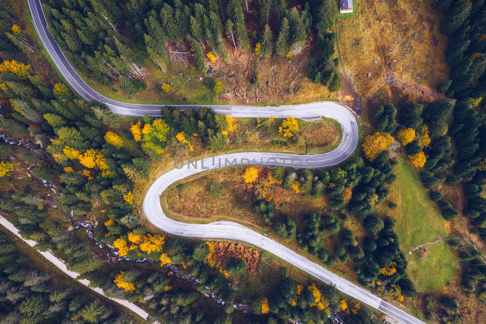 Curved bending road in the forest. Aerial image of a road. Forrest pattern. Scenic curvy road seen from a drone in autumn. Aerial top down view of zig zag winding mountain road, drone shot.