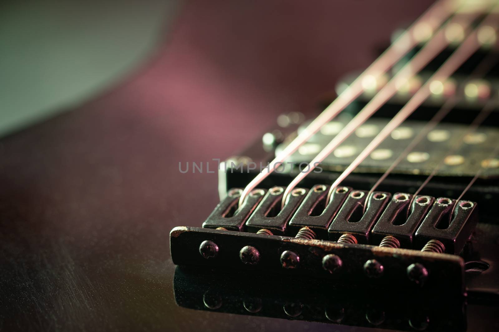 Rust bridge serves to fasten or tighten the string. Black vintage electric guitar in dark. Closeup and copy space. Concept of good memory About retro musical instruments and rock music.