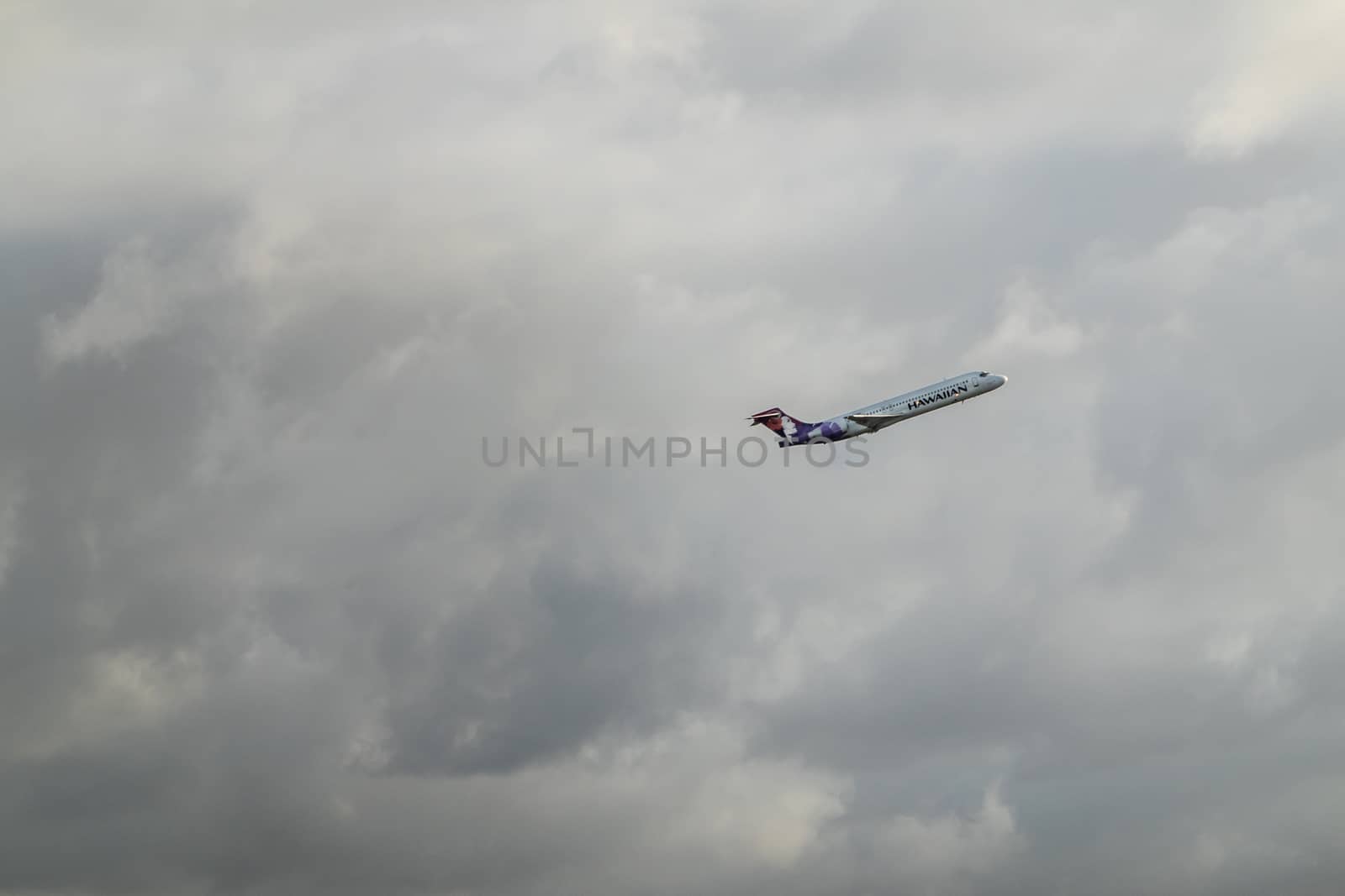 Hilo, Hawaii, USA. - January 14, 2020: Closeup of Hawaiian airline fliying off into gray cloudscape from airport.