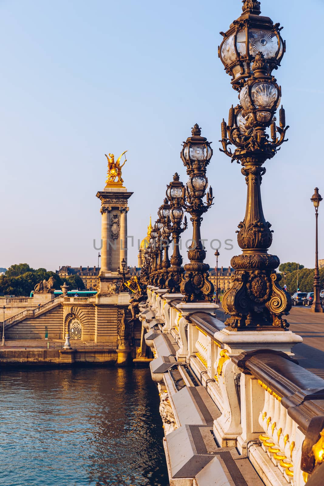 Pont Alexandre III bridge over river Seine in the sunny summer morning. Bridge decorated with ornate Art Nouveau lamps and sculptures. The Alexander III Bridge across Seine river in Paris, France.