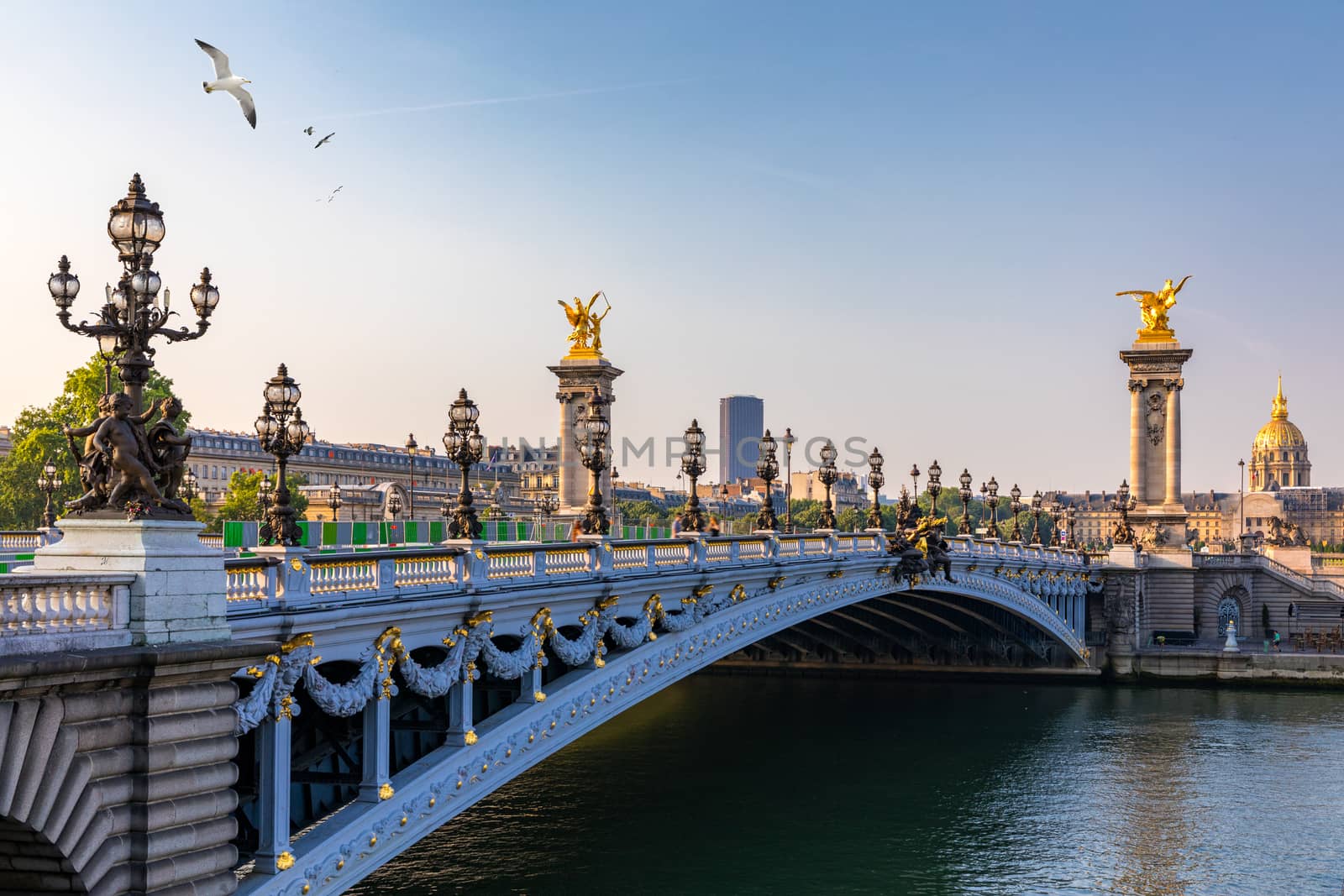 Pont Alexandre III bridge over river Seine in the sunny summer morning. Bridge decorated with ornate Art Nouveau lamps and sculptures. The Alexander III Bridge across Seine river in Paris, France.