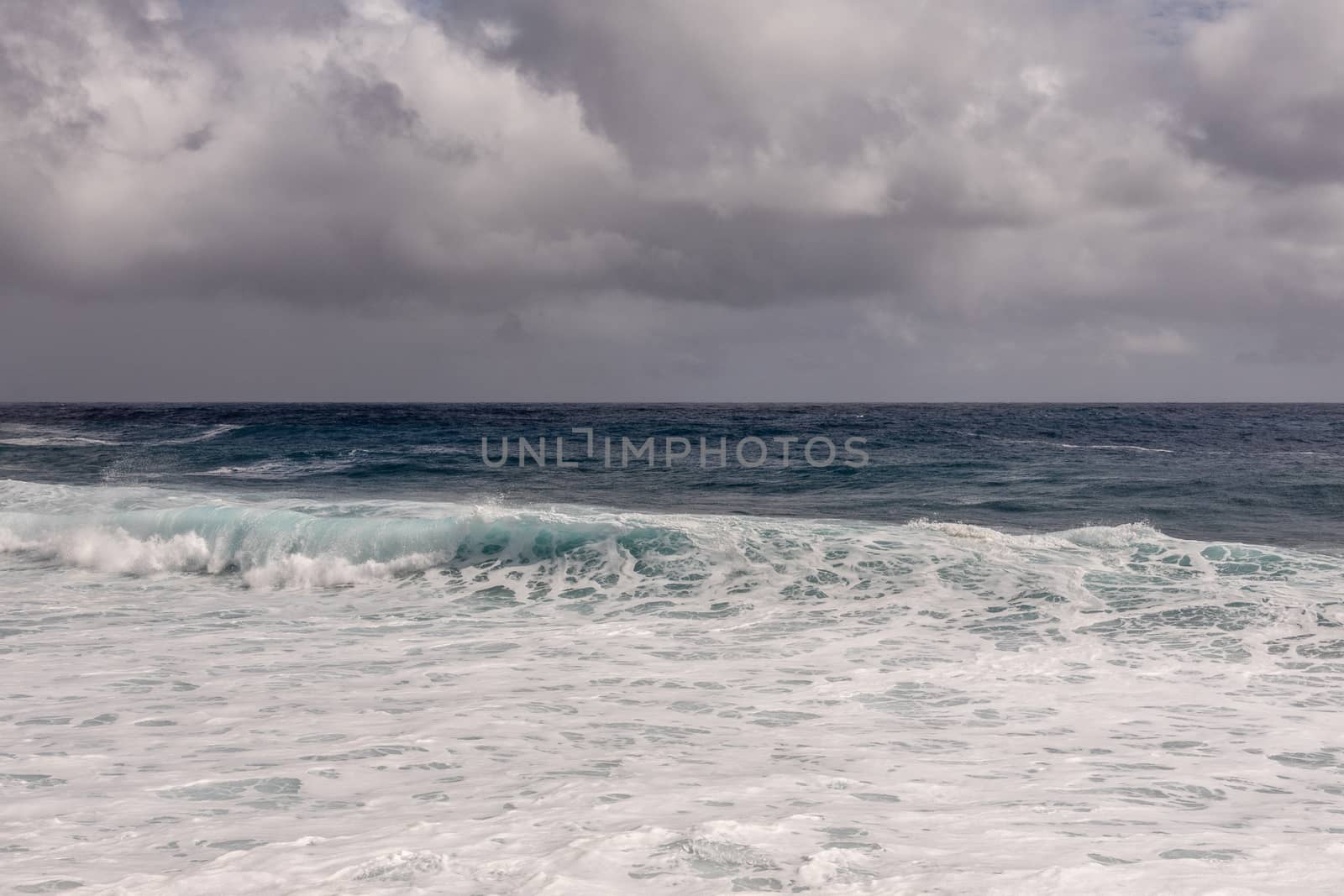 White surf of dark ocean under heavy cloudscape on Kaimu Beach,  by Claudine