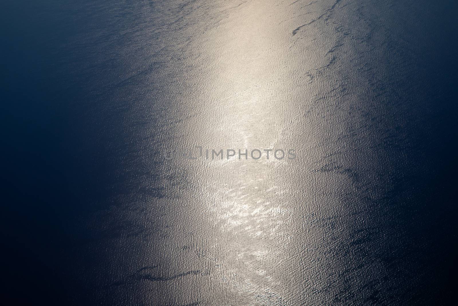 Sunlight twinkling and reflecting off sea water. Sparkles on water. Sun reflecting on the ocean surface, view from the plane, concept of travel. 