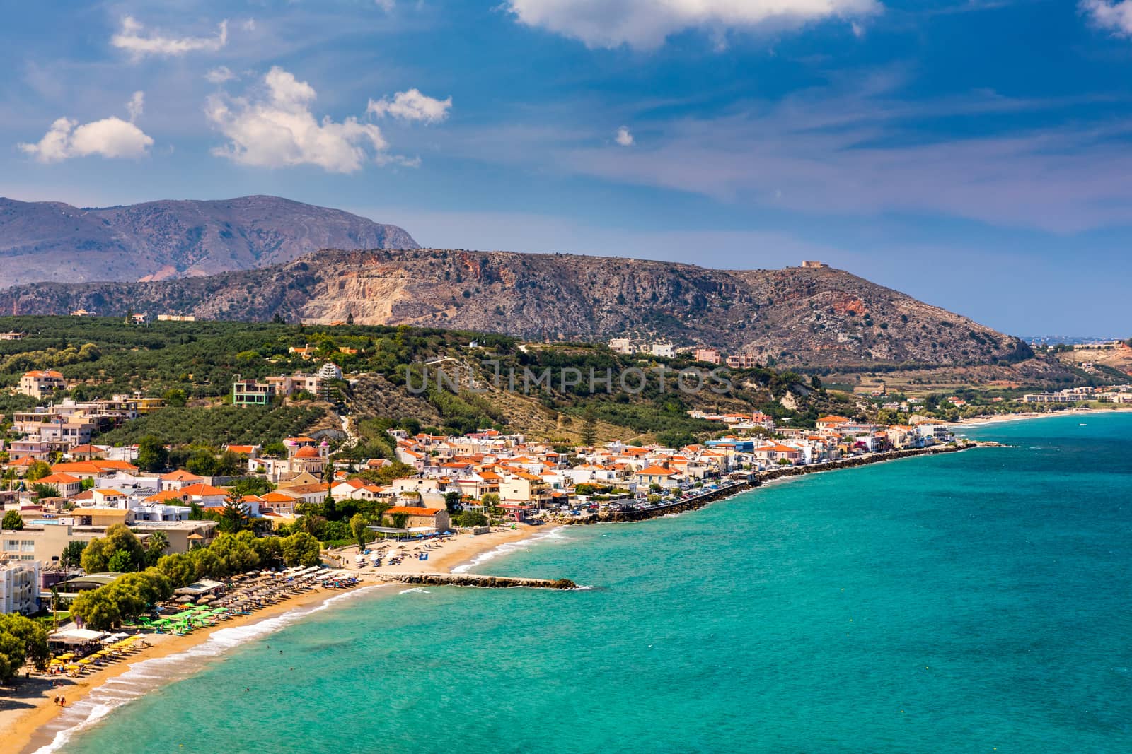 Greek holidays, beautiful Kalyves village with turquoise sea in Crete island, Greece. View of Kalyves beach, Crete. Tourists relaxing on the beach and views to the mountains, Kalyves, Crete, Greece